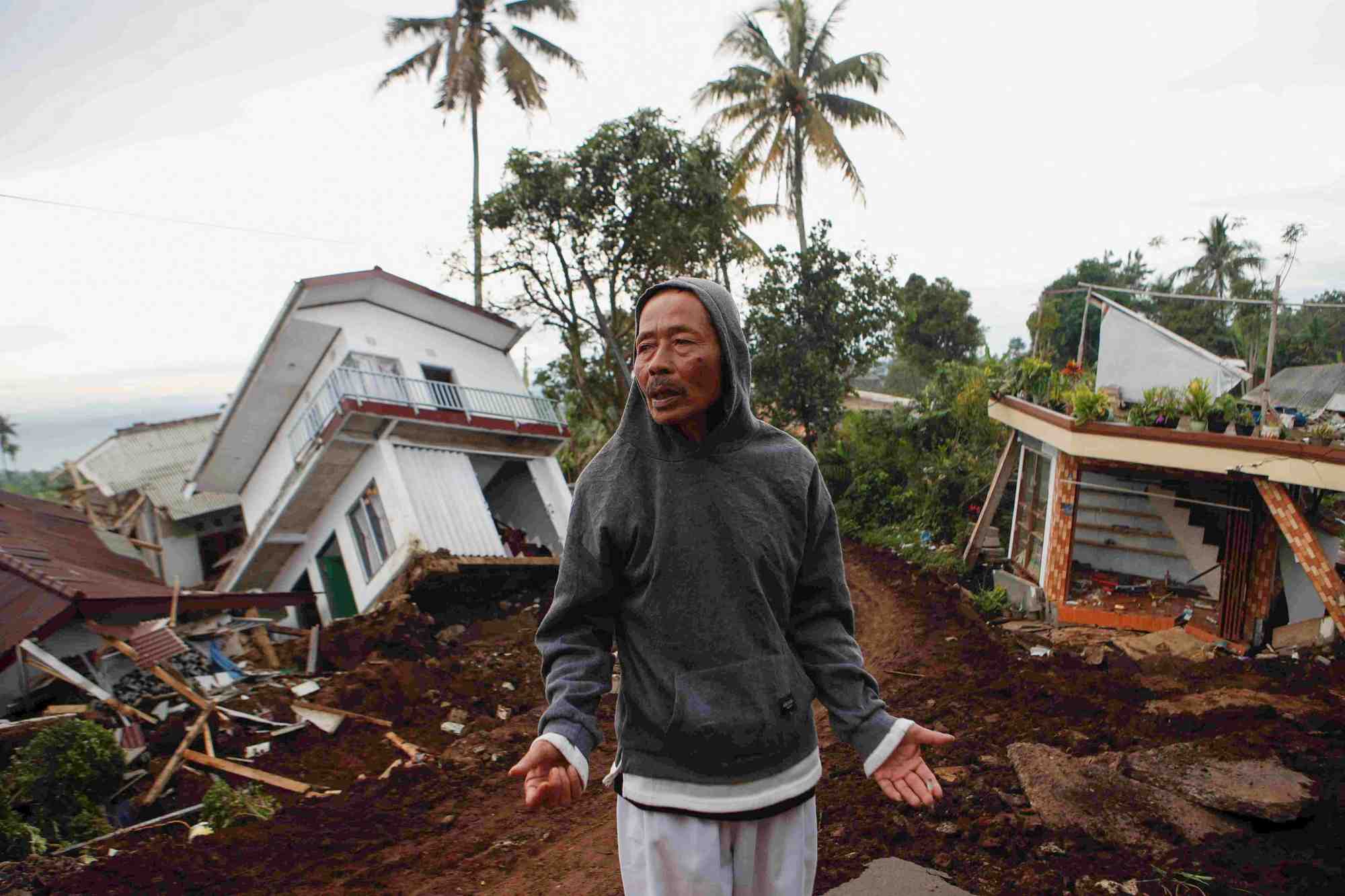 Un homme pres de maisons gravement endommagees apres le tremblement de terre de lundi a cianjur, en indonesie