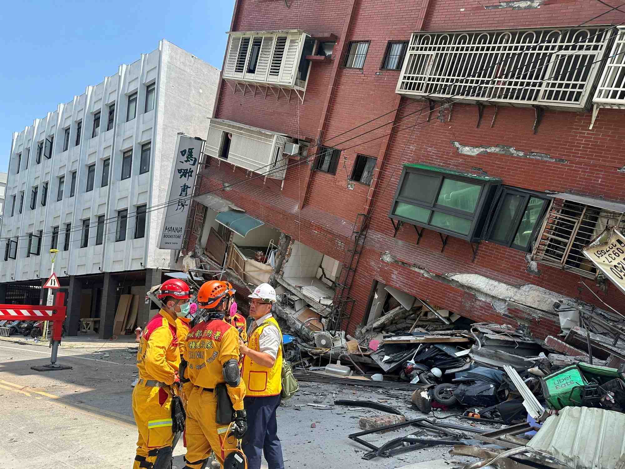 Des pompiers pres d'un batiment s'etant effondre a la suite du tremblement de terre, a taiwan