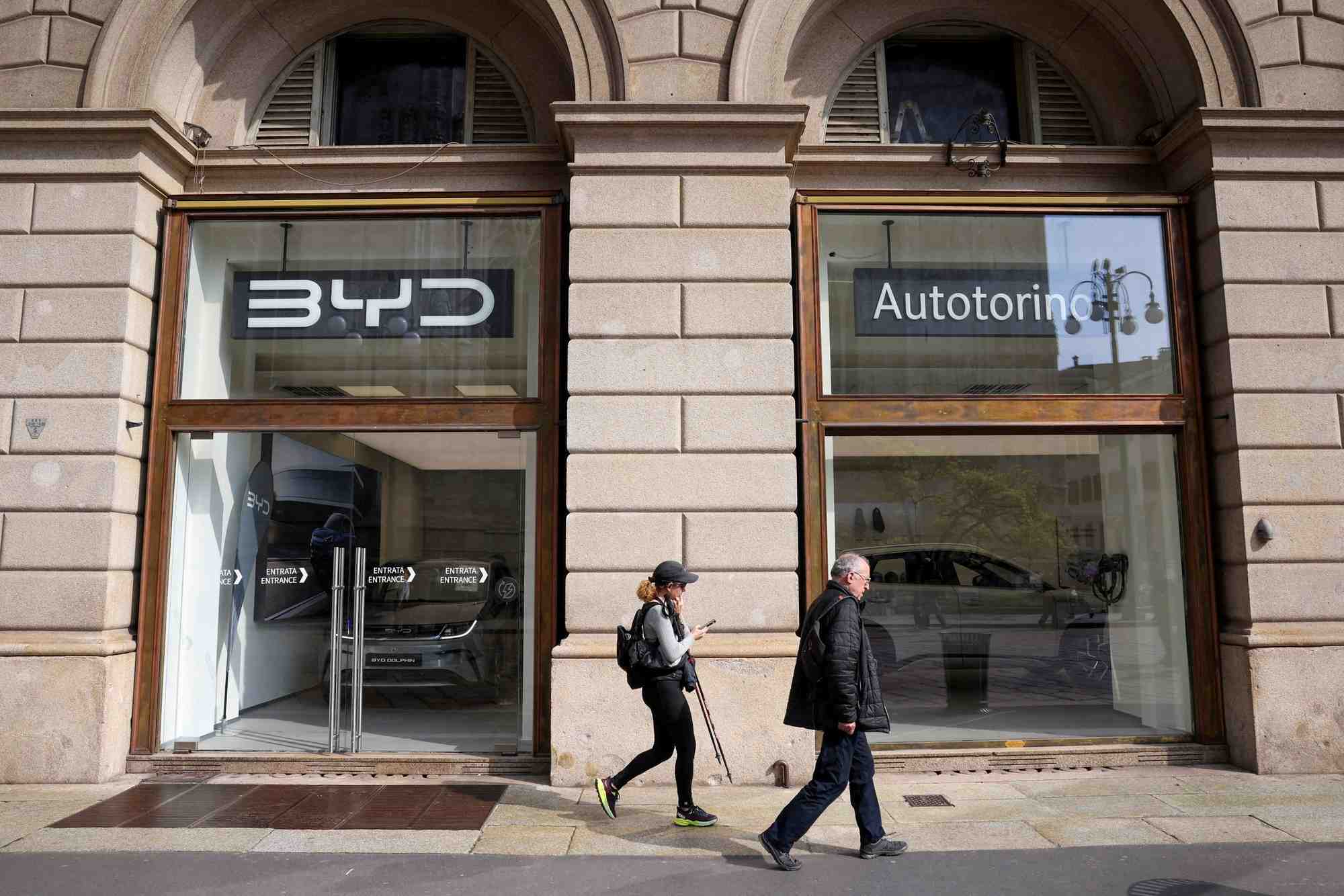 Des personnes marchent devant un magasin byd auto a milan