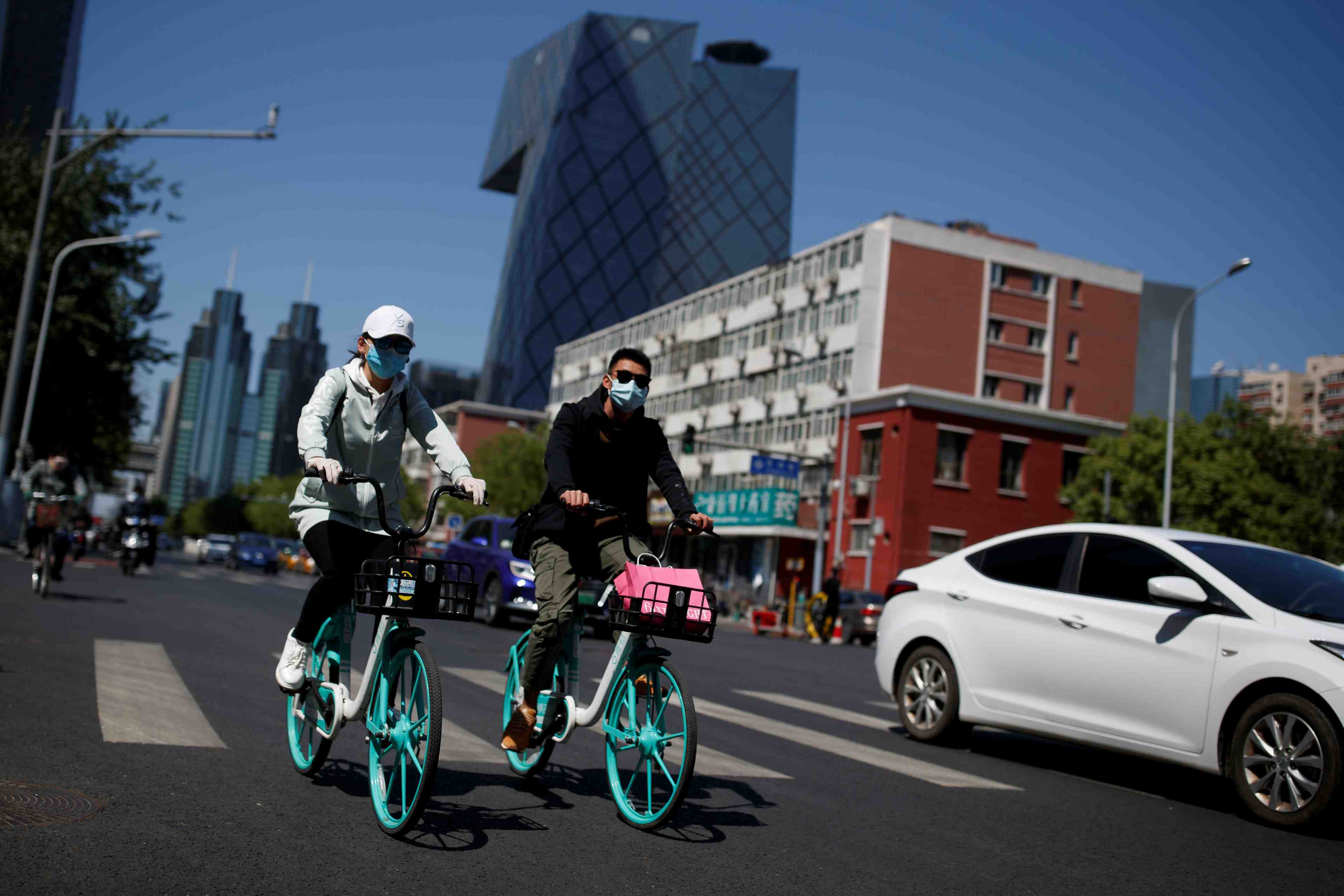 People wearing protective masks ride bikes in the central business district on a “blue sky day" in beijing as the spread of the novel coronavirus disease (covid-19) continues