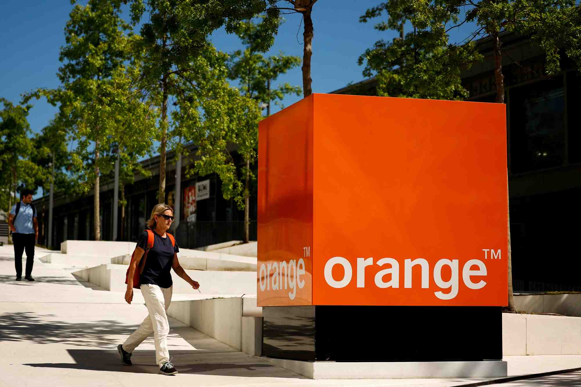 Une femme passe devant le logo d'orange au siege de la societe a issy-les-moulineaux