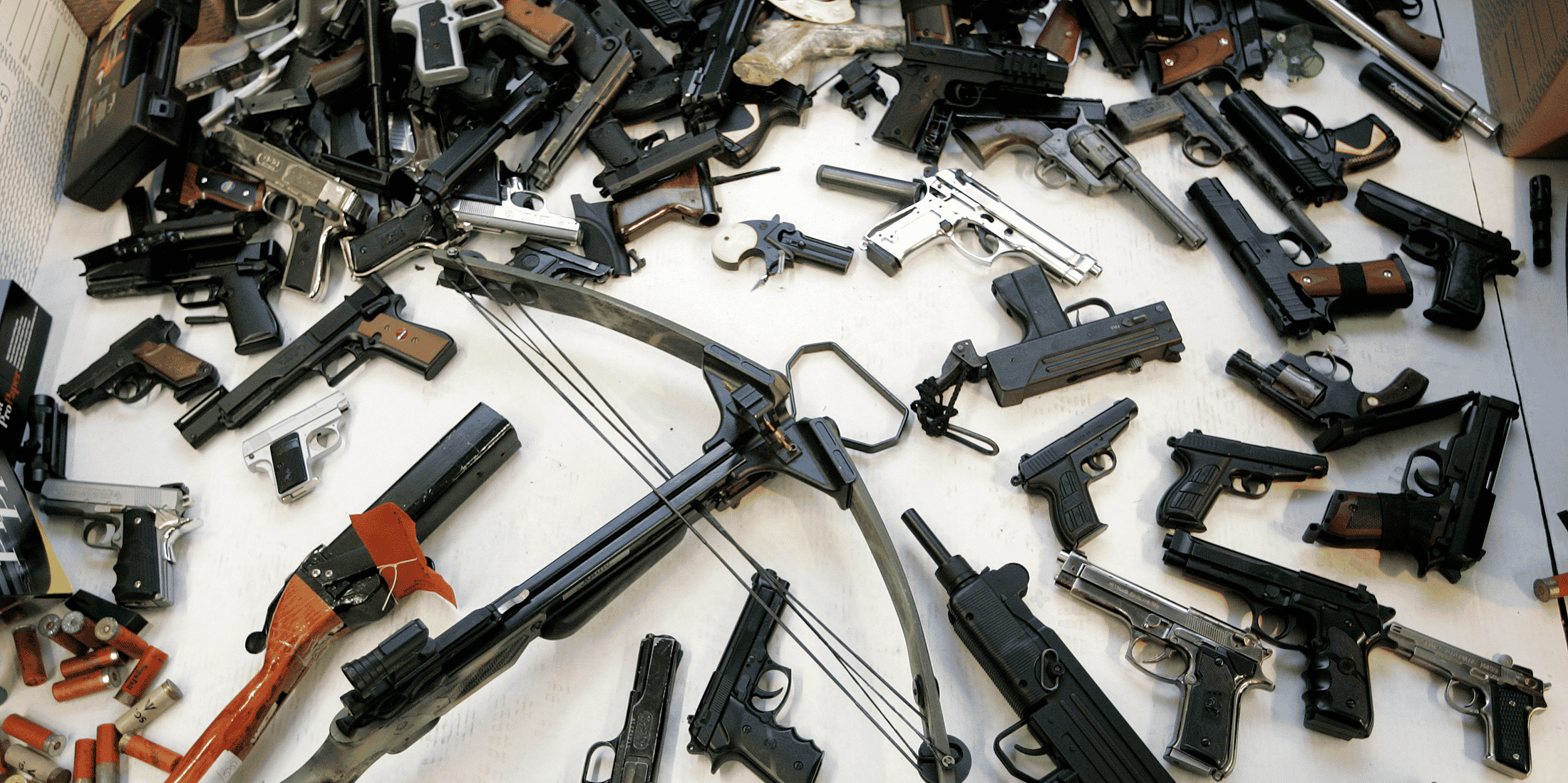 Un arsenal d'armes à feu (pistolets, munitions, fusils) posé sur une table à Manchester