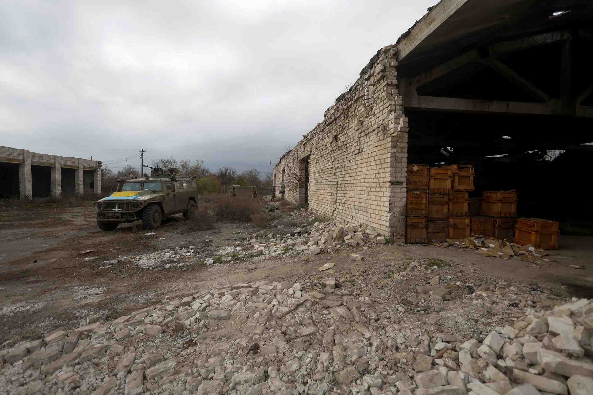 Des membres des services ukrainiens marchent vers un vehicule blinde de transport de troupes russe precedemment capture dans le village de blahodatne, dans la region de kherson