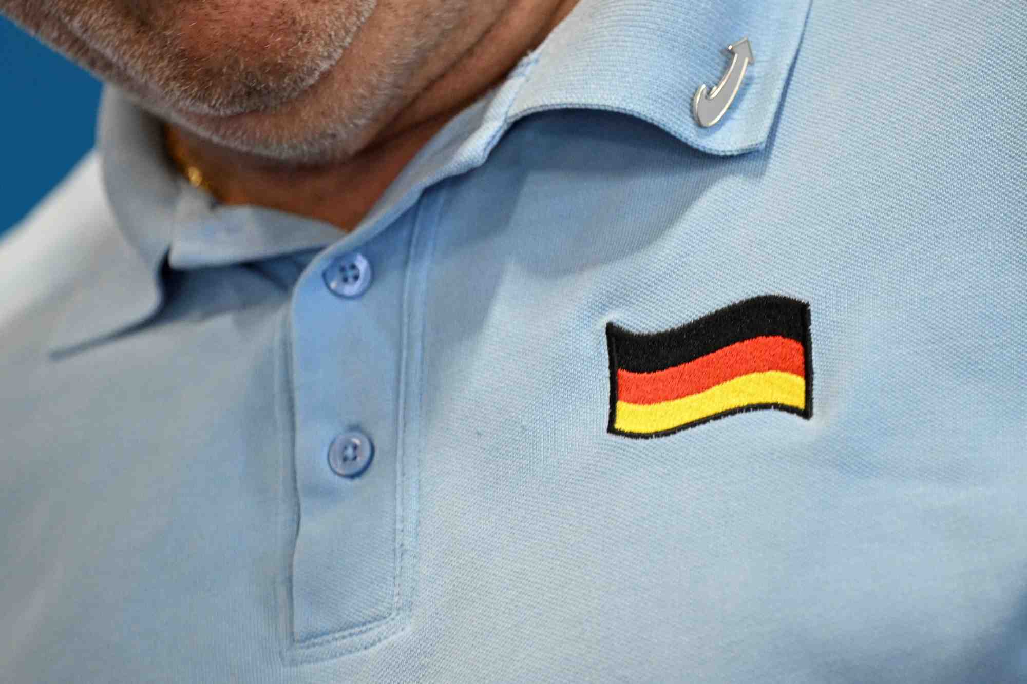 Une personne arbore le drapeau allemand et un pin's de l'afd