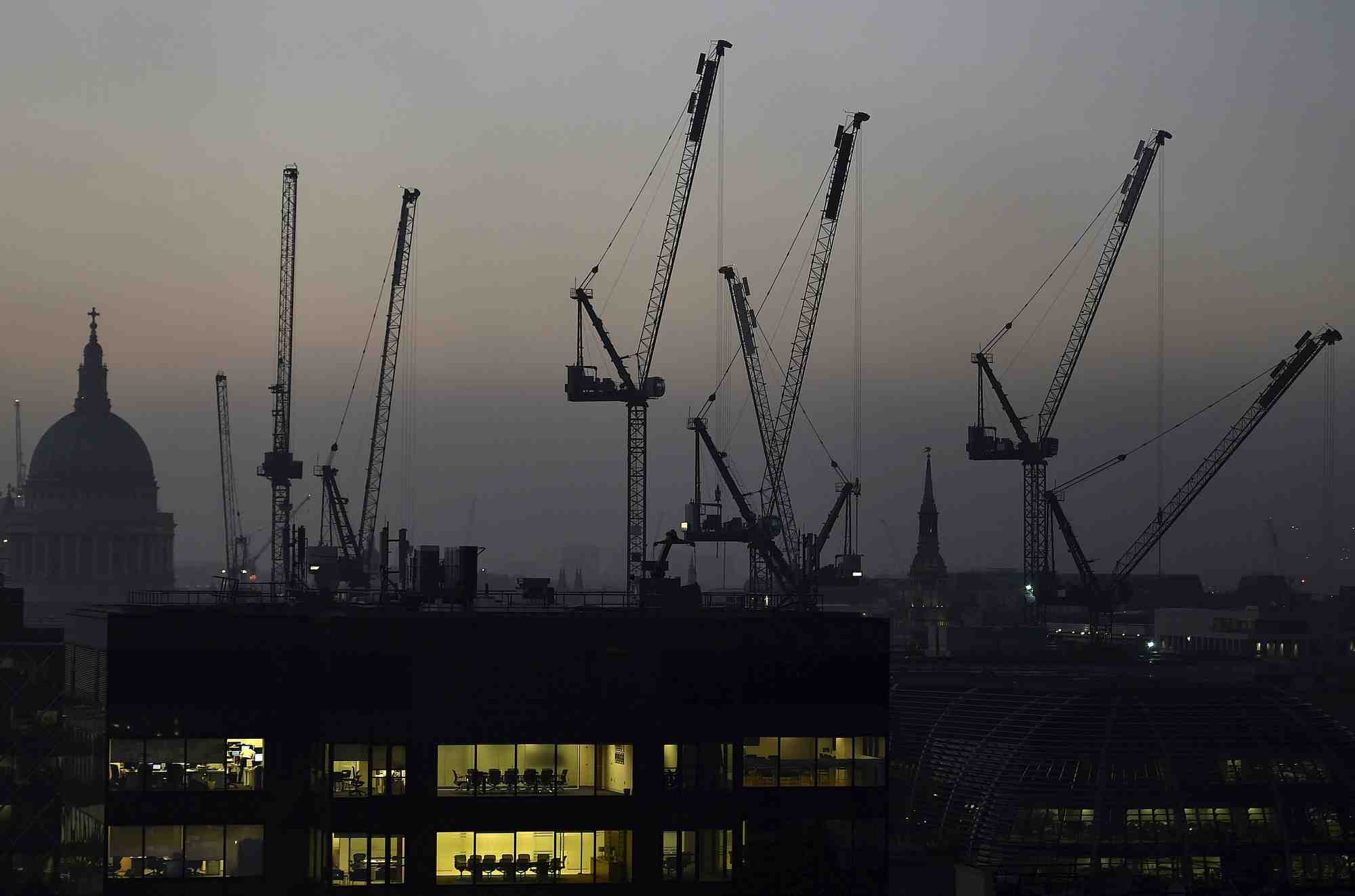 Des bureaux au crepuscule devant la cathedrale saint-paul et des grues de construction a londres