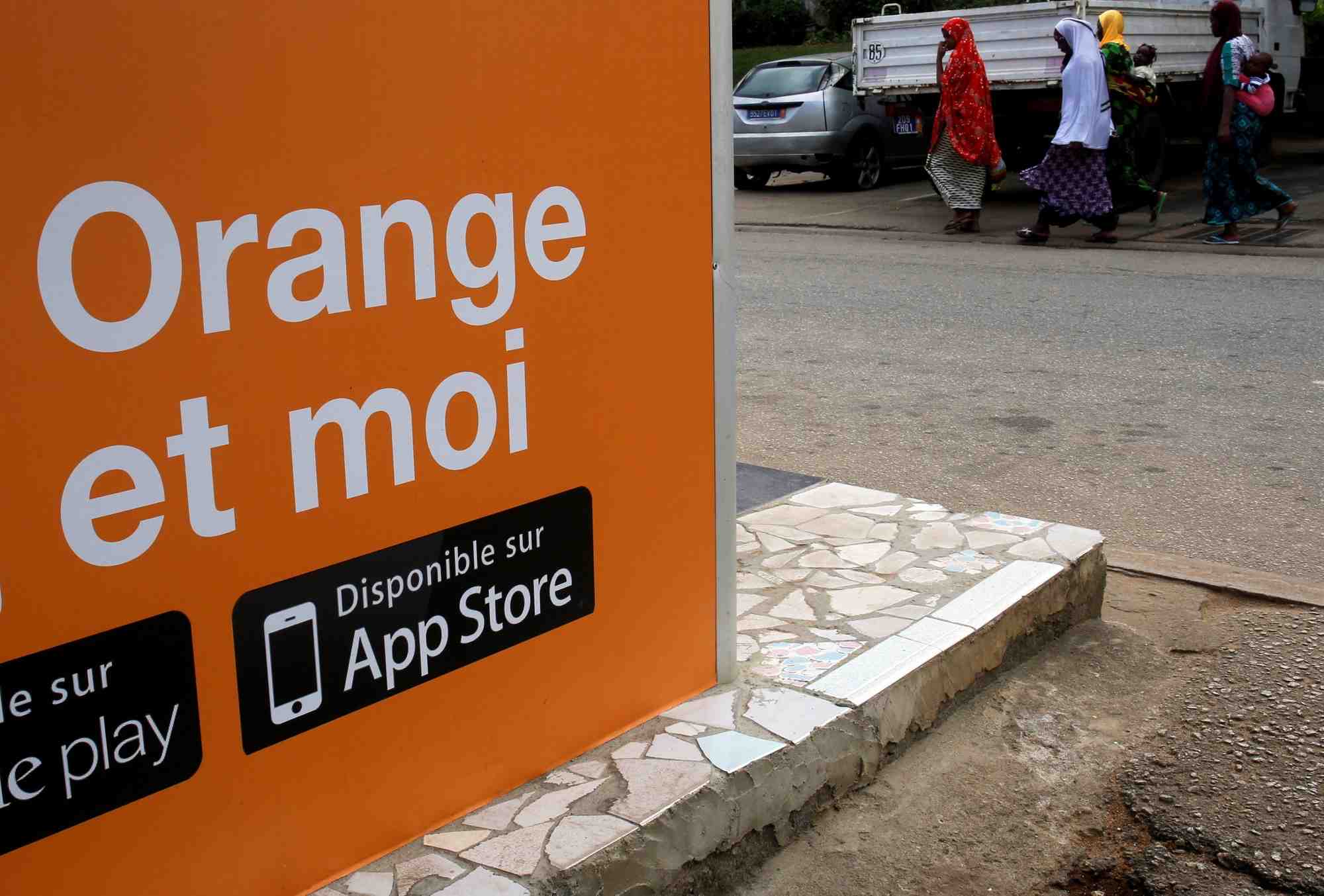 Des personnes marchent pres d'un kiosque orange money, alors qu'orange lance ses premiers services orange bank a abidjan