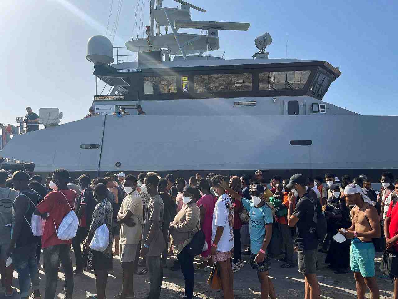 Des migrants attendent dans le port de lampedusa, en italie