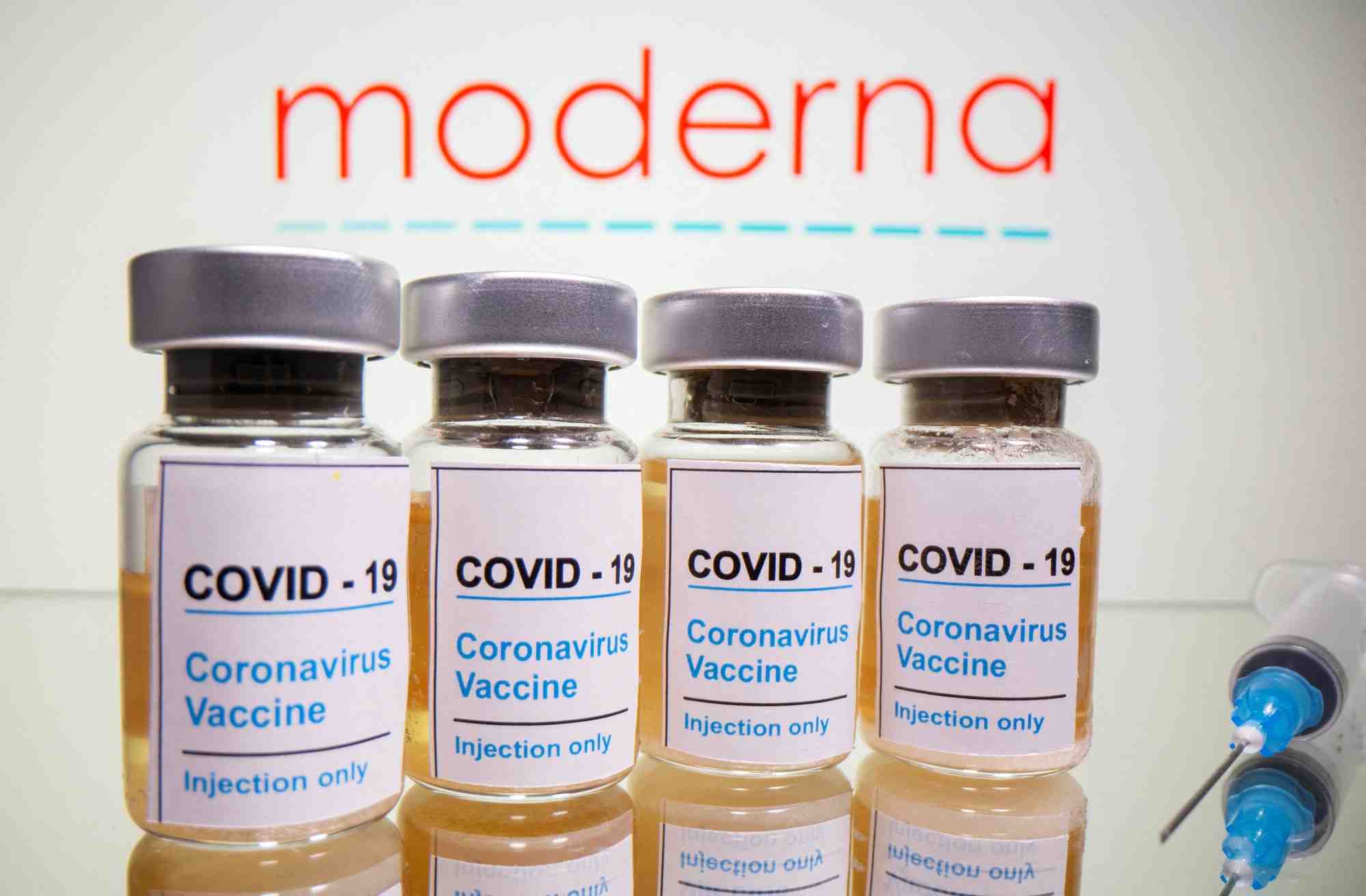 Flacons avec un autocollant indiquant "covid-19 / vaccin contre le coronavirus / injection uniquement" et une seringue medicale devant le logo de moderna