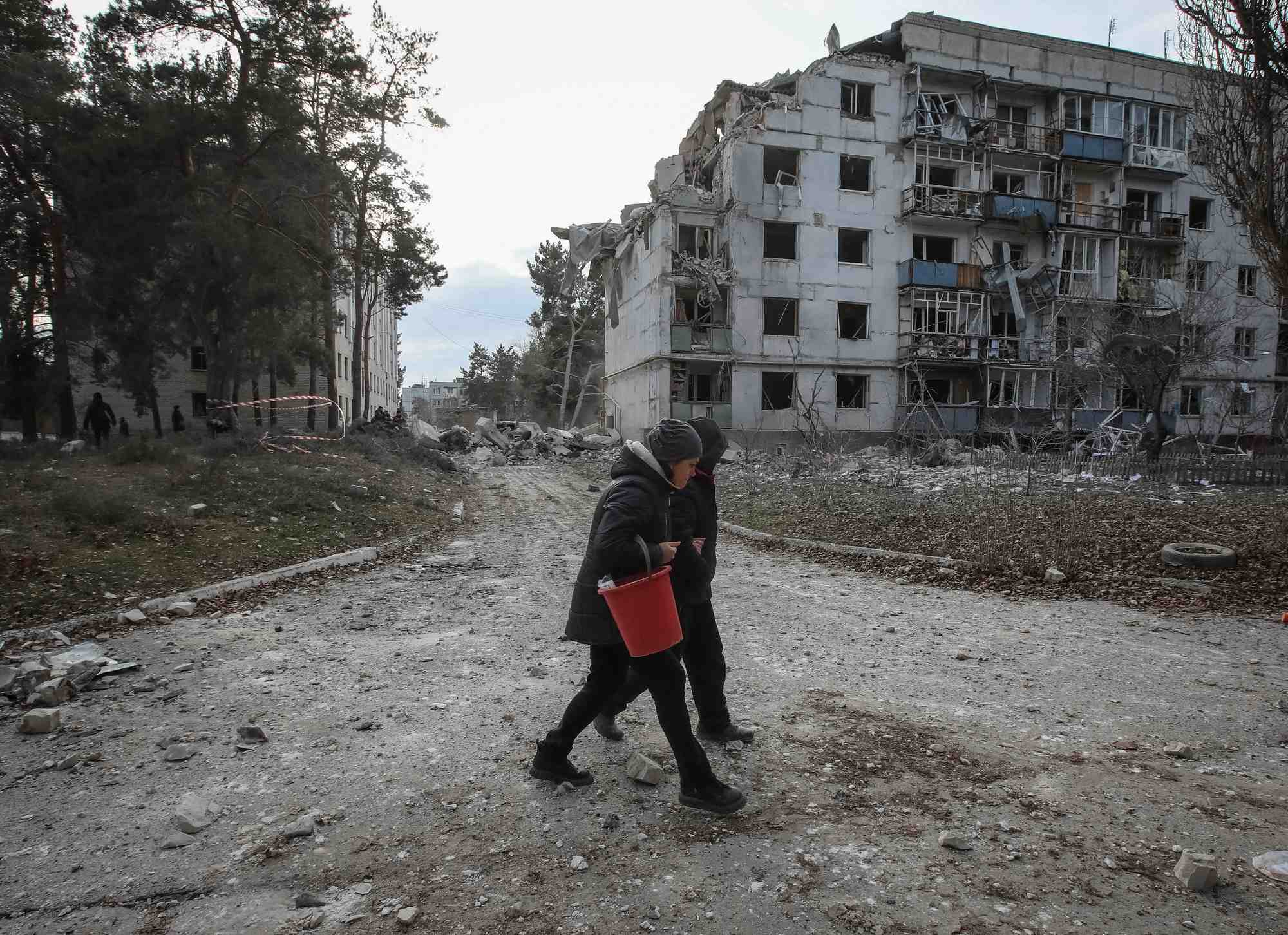 Des habitants marchent pres d'un batiment residentiel endommage par un tir de missile russe, pres de la ville de chuhuiv, dans la region de kharkiv