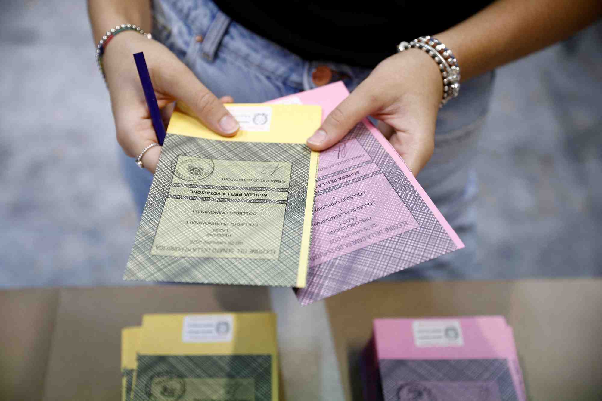 Une personne tient des bulletins de vote dans un bureau de vote