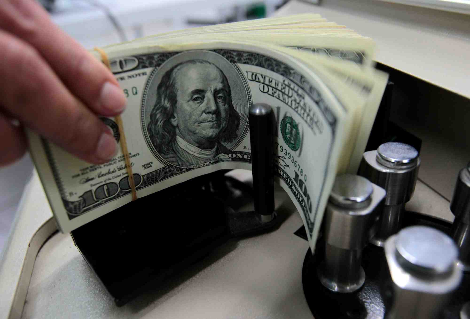 Un employe de banque compte des billets de cent dollars americains a la kasikornbank a bangkok