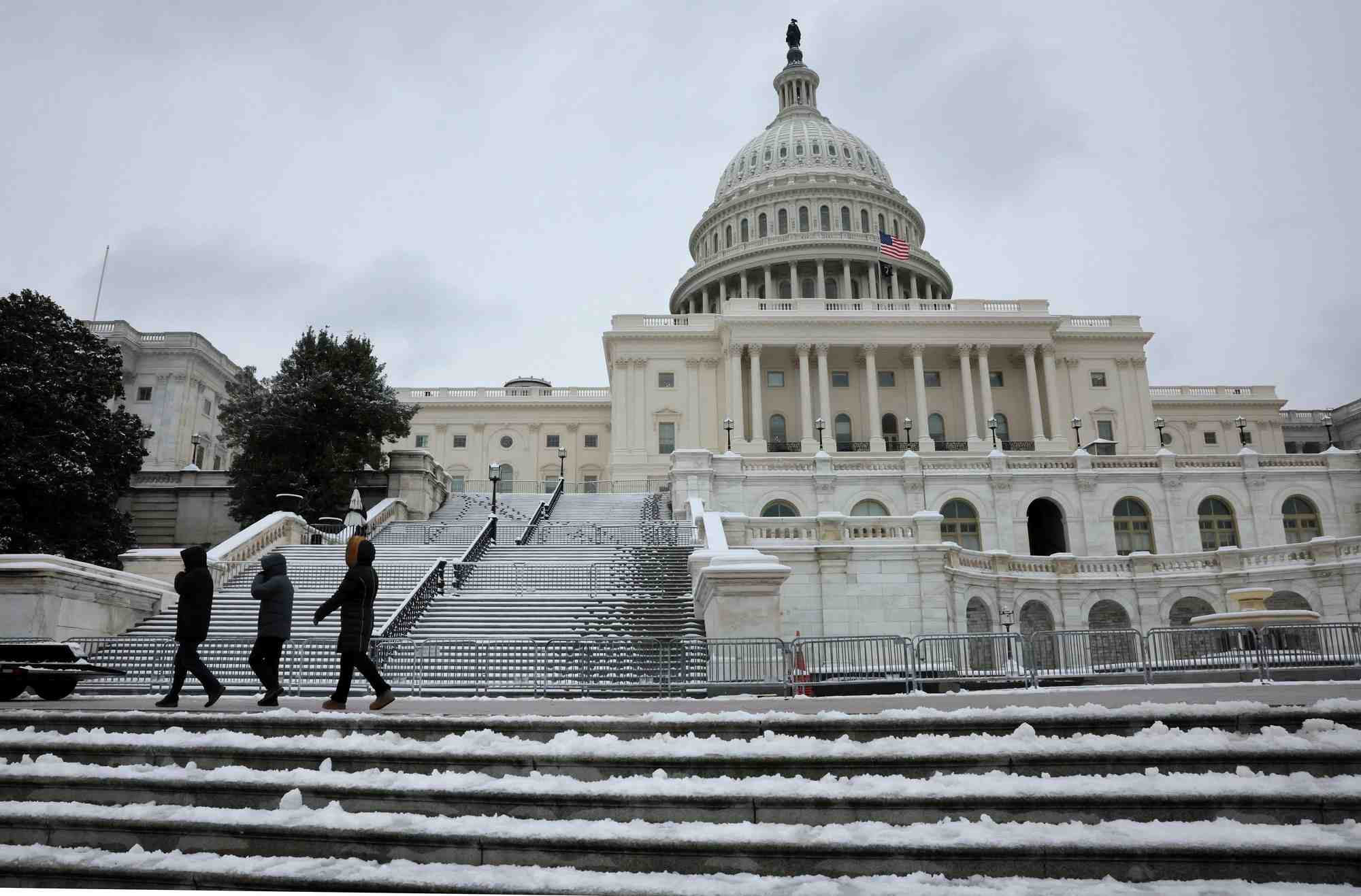 Des passants devant le capitole enneige a washington