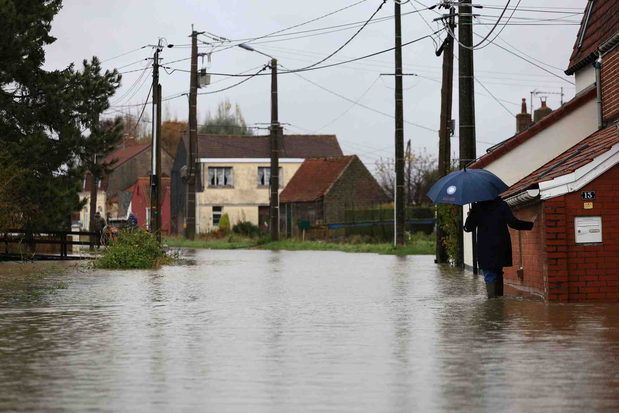 Une femme marche dans une rue inondee du doulac, dans le nord de la france