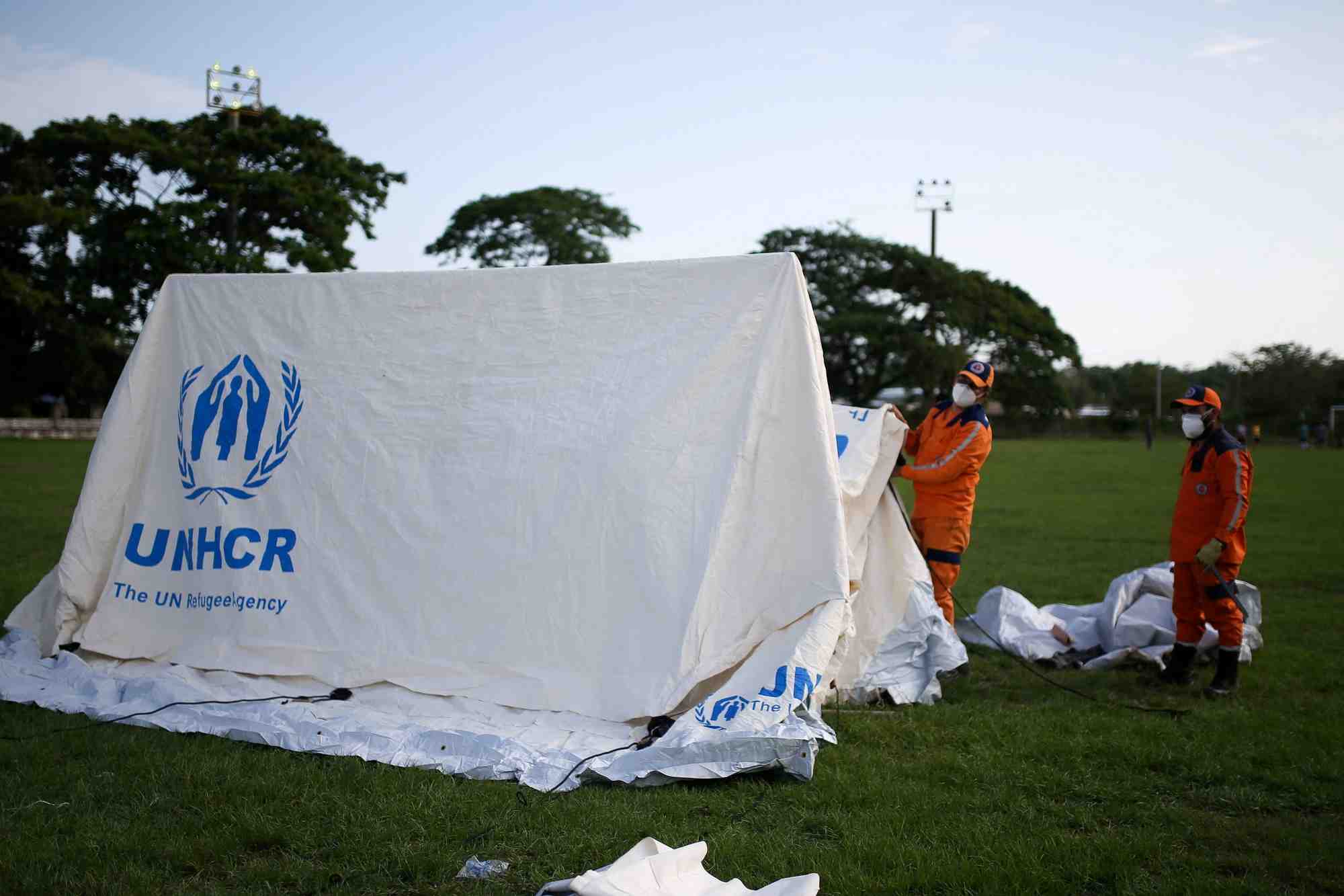 Des employes de la defense civile colombienne montent des tentes pour un camp qui servira d'abri aux migrants