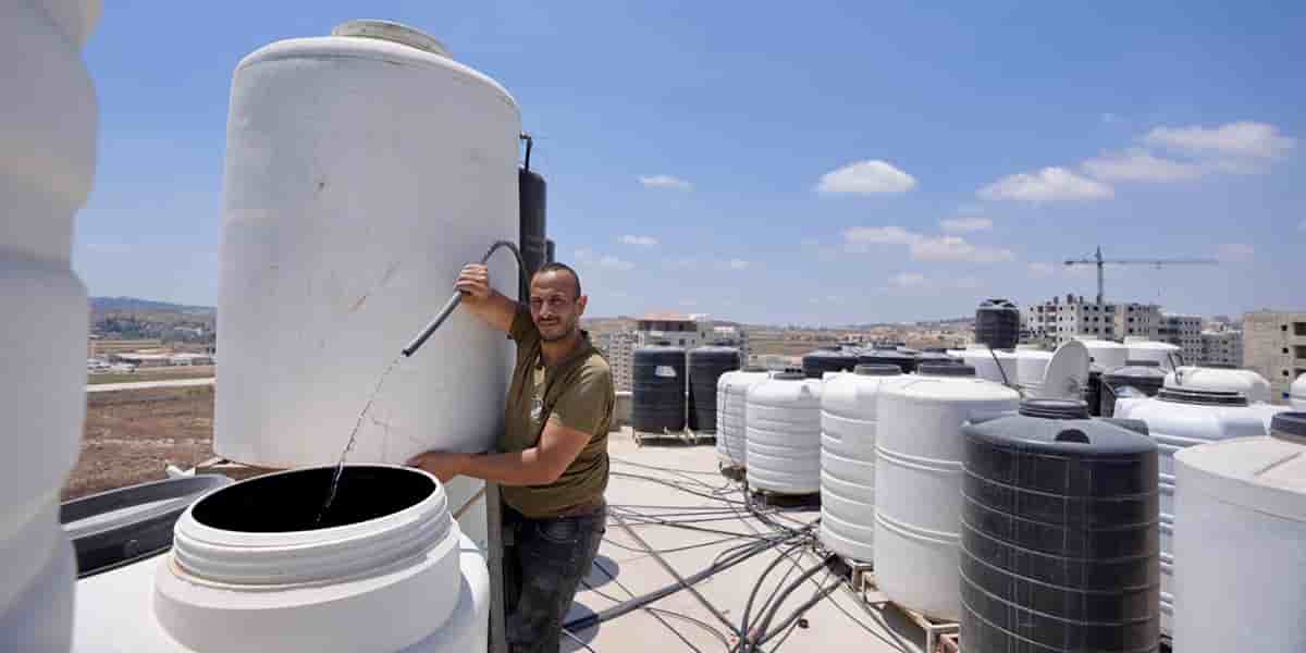 Un habitant de Kufr Aqab au milieu des réservoirs d’eau d’un immeuble, le 29 juillet.