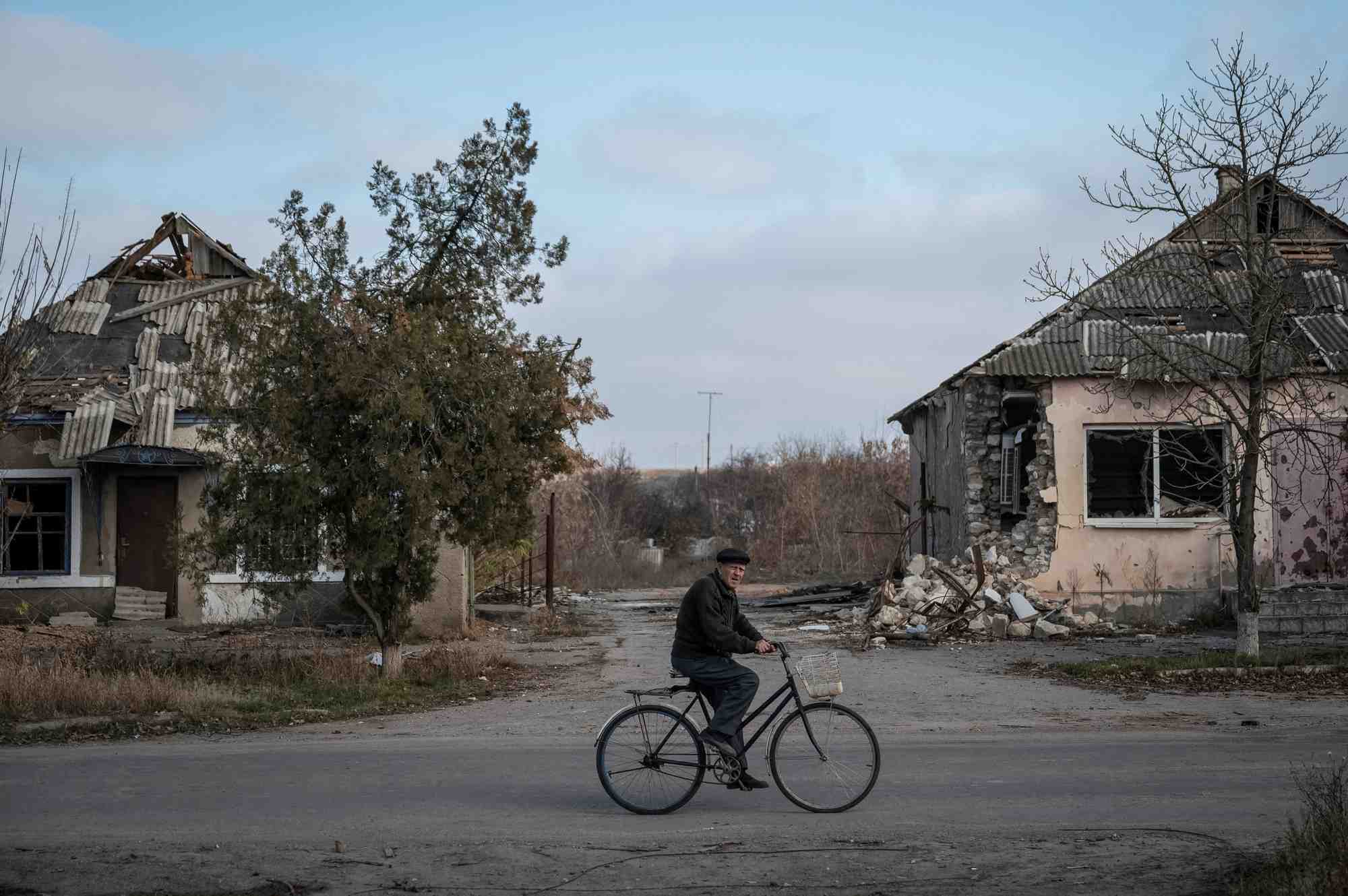Un habitant fait du velo pres de maisons detruites dans le village d'arkhanhelske, dans la region de kherson