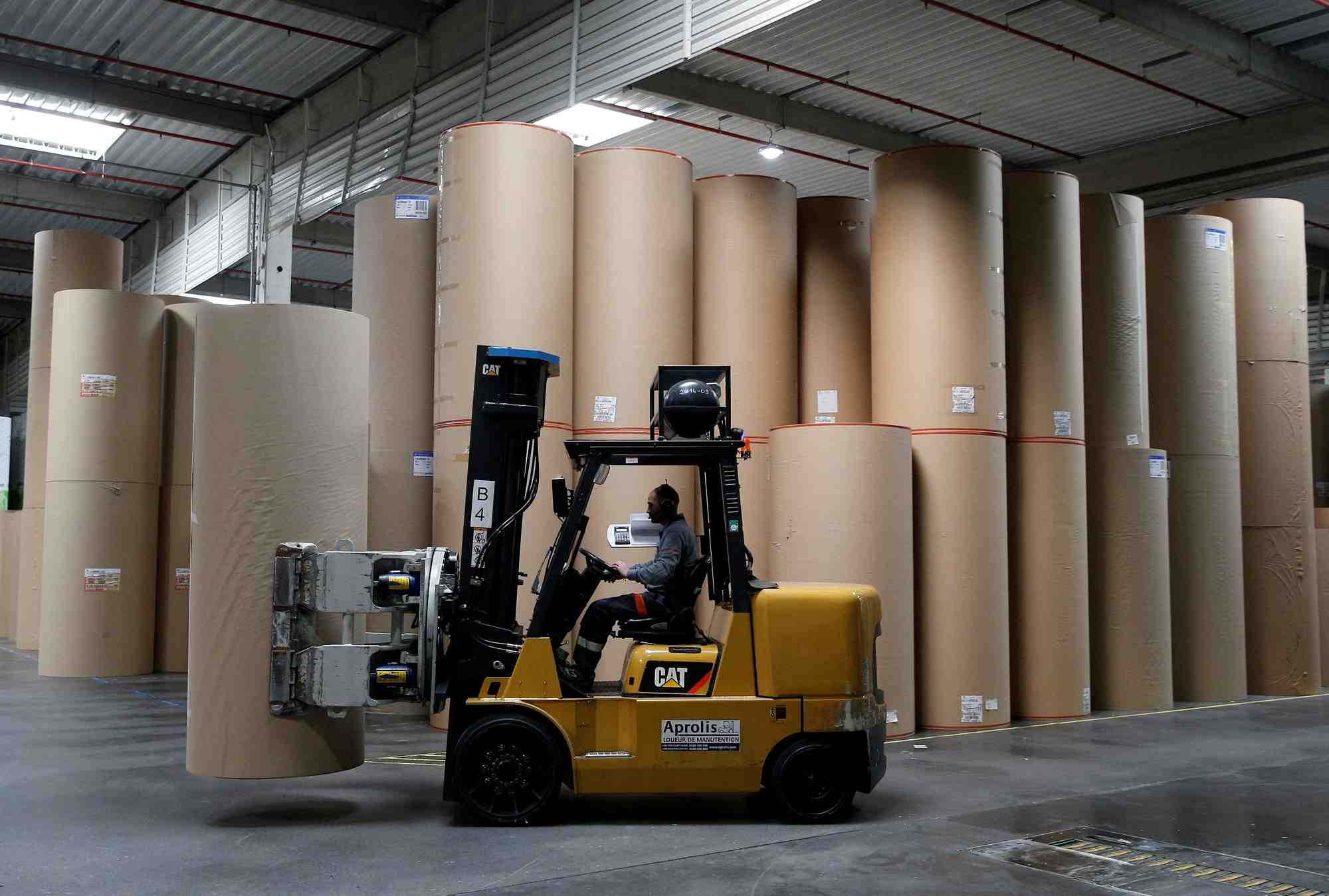 Un employe transporte une bobine de papier geante