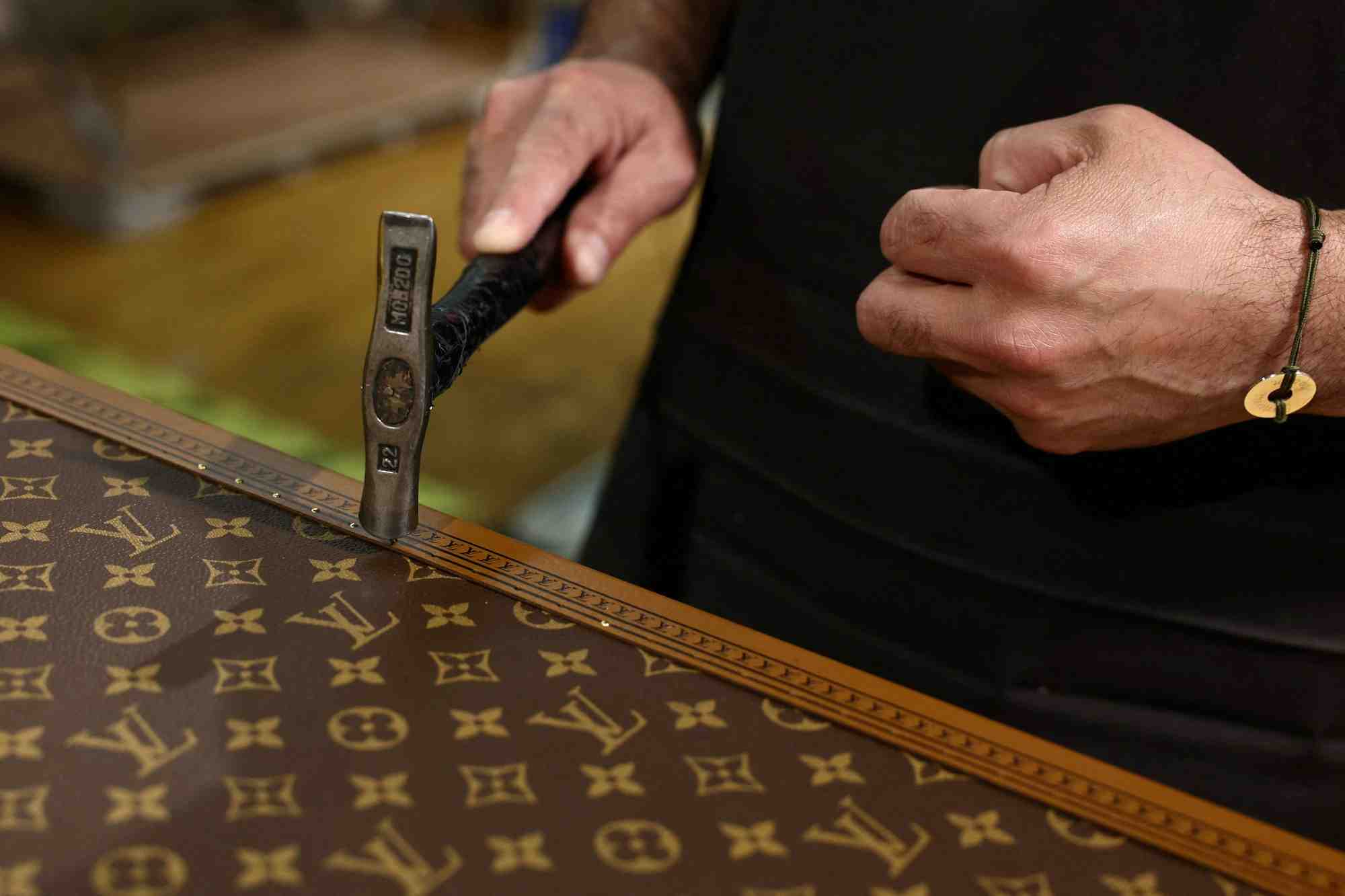 Un employe travaille sur la fabrication d'une malle louis vuitton