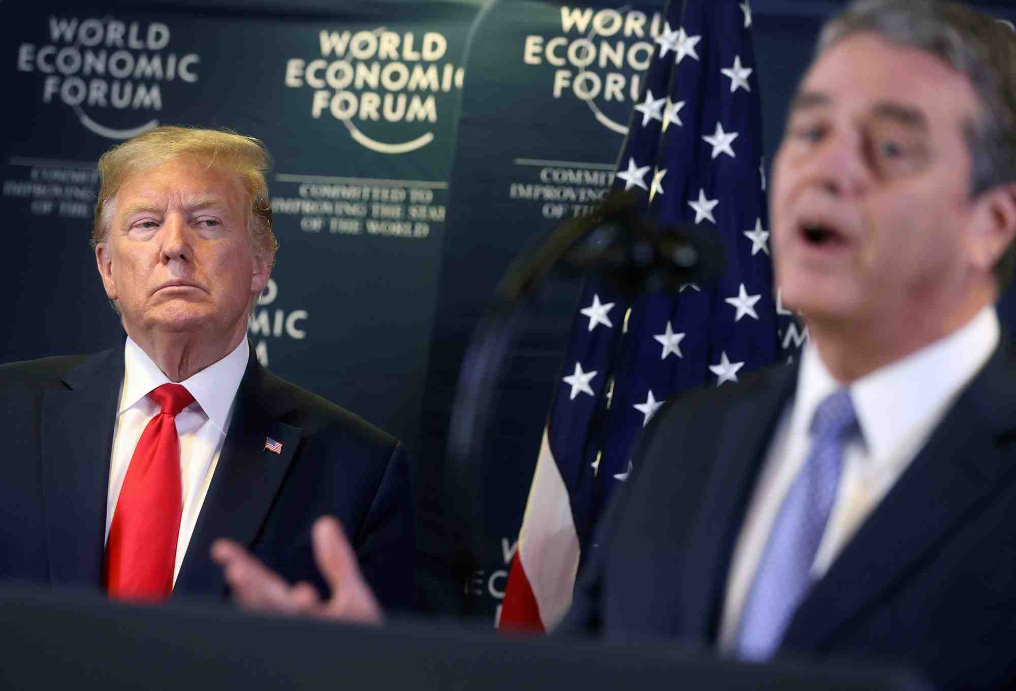 Roberto Azevedo, président de l'OMC (au flou, à dr.), lors d'un discours à Davos (Suisse) le 22 janvier 2020, sous le regard de Donald Trump qui n'a eu de cesse de critiquer les décisions de l'Organisation mondiale du commerce depuis le début de son mandat.