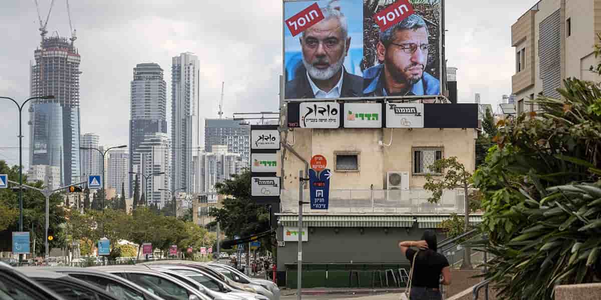 Une femme marche près d’un panneau affichant les portraits des leaders du Hamas avec le slogan « assassinés », à Tel Aviv, vendredi.
