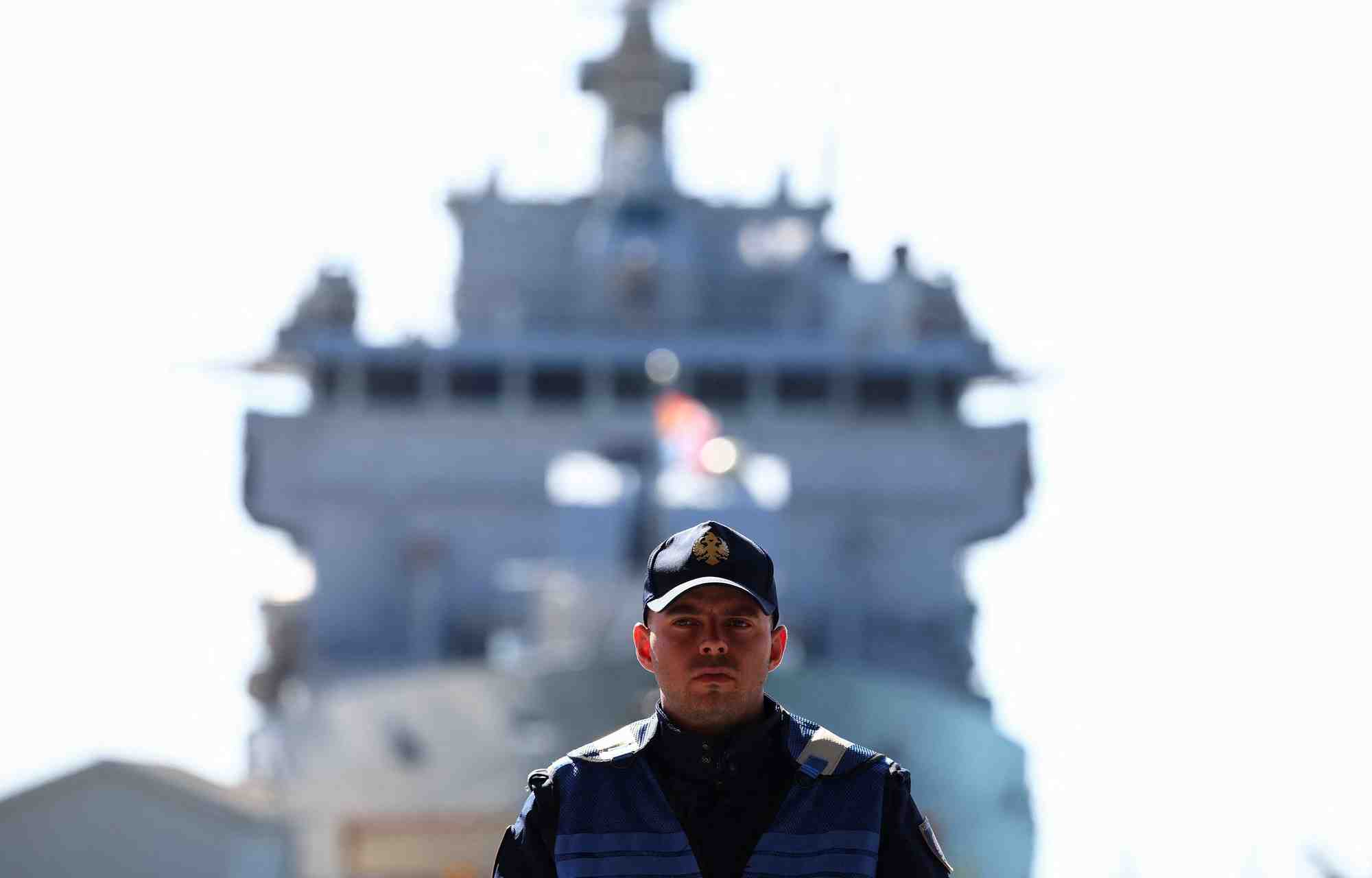 Un officier de police albanais se tient a l'entree du port le jour de l'arrivee des migrants sur le navire de la marine italienne libra en albanie