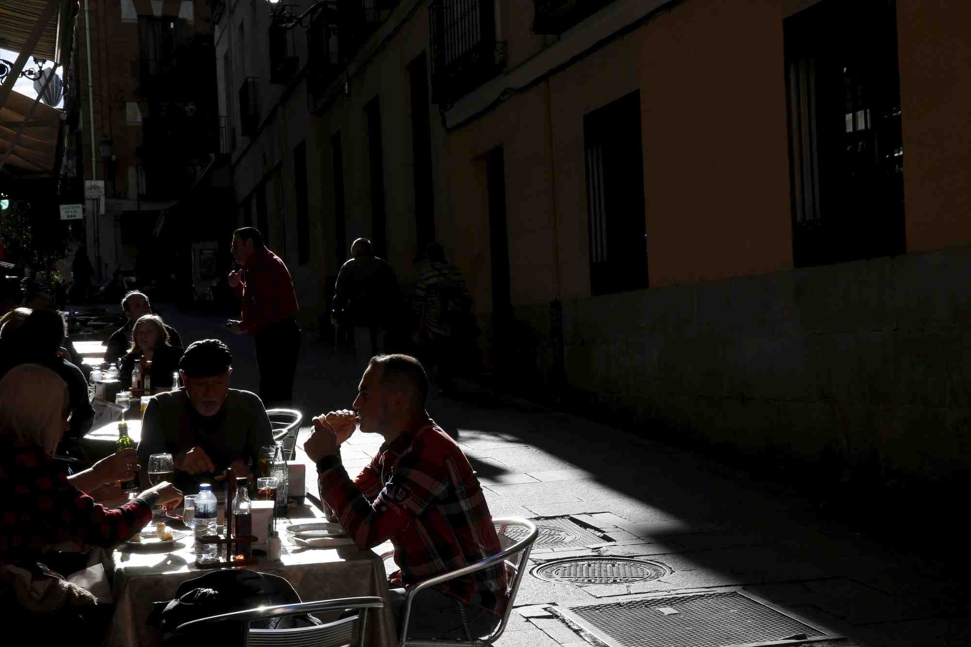 Des personnes dejeunent a des tables en plein air dans un restaurant du centre de madrid