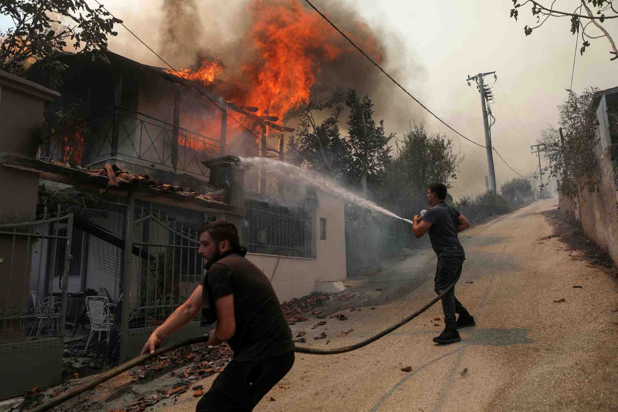Des volontaires tentent d'eteindre un incendie dans une maison pres d'athenes, en grece