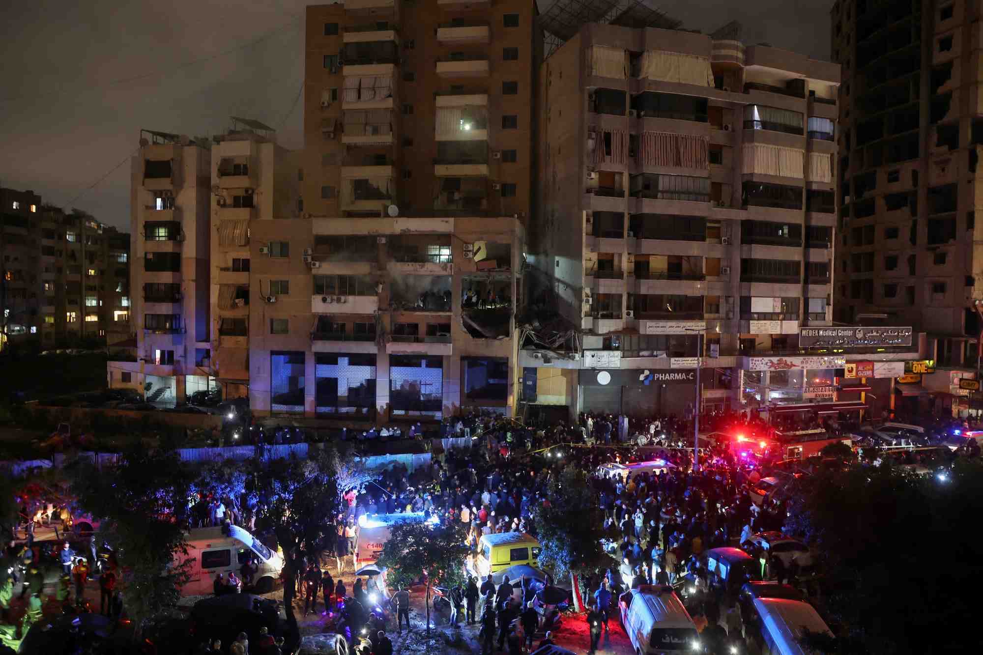 Photo des gens qui se rassemblent pres d'un site endommage suite a une explosion a dahiyeh, dans la banlieue de beyrouth