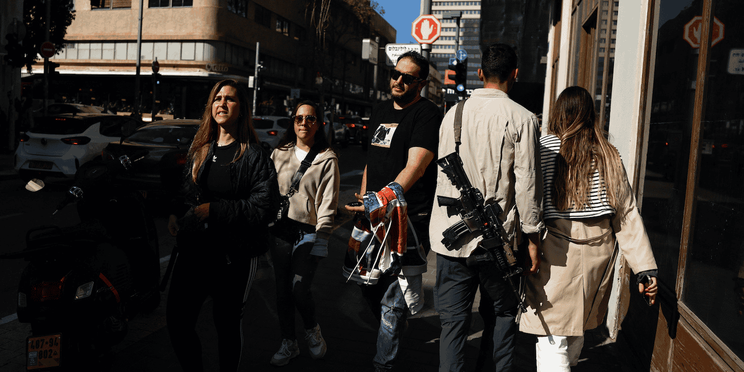 Piétons armés dans la ville de Tel Aviv, vendredi, témoignant du climat de guerre qui règne dans le pays.