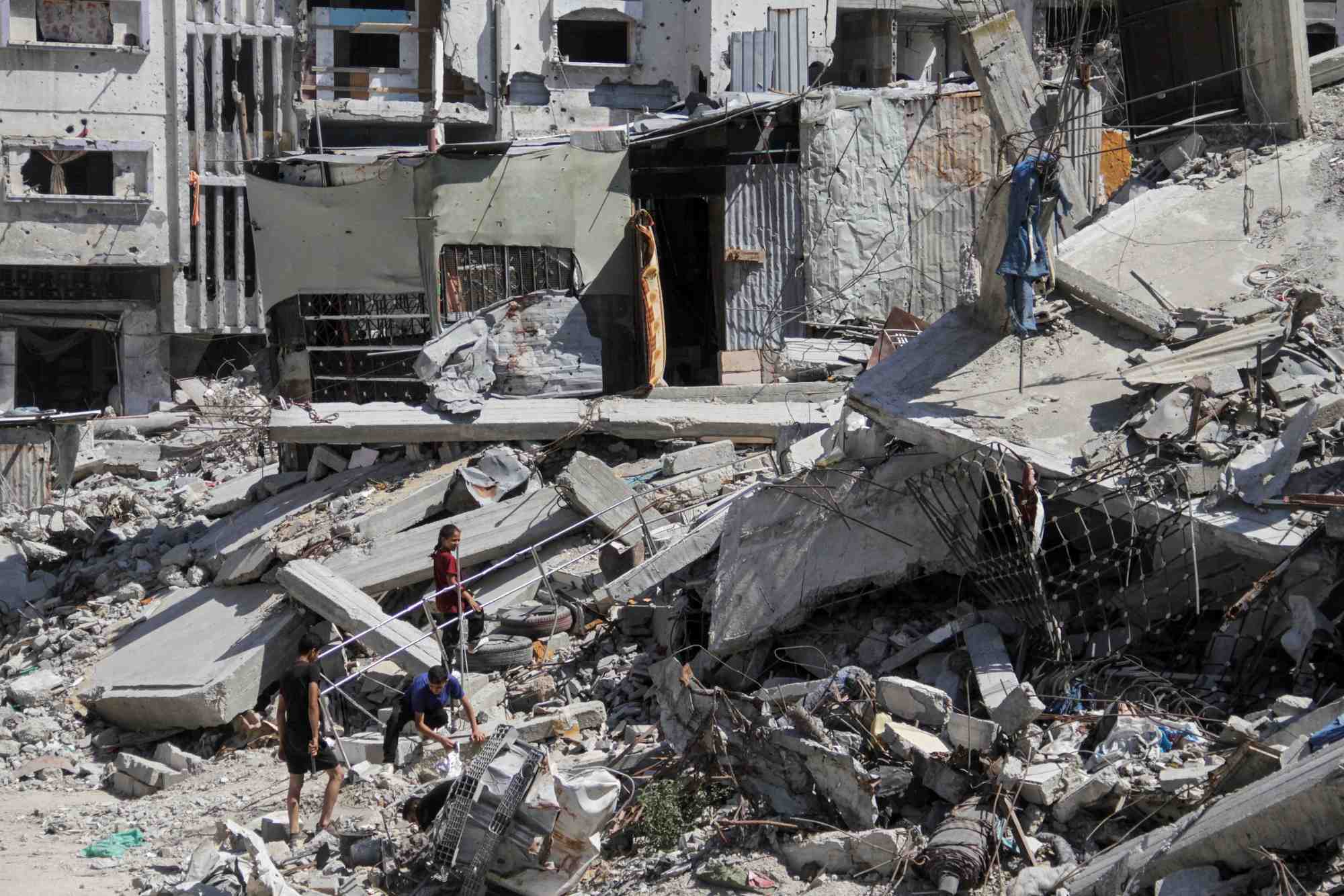Des palestiniens marchent parmi les decombres de batiments detruits a beit lahia
