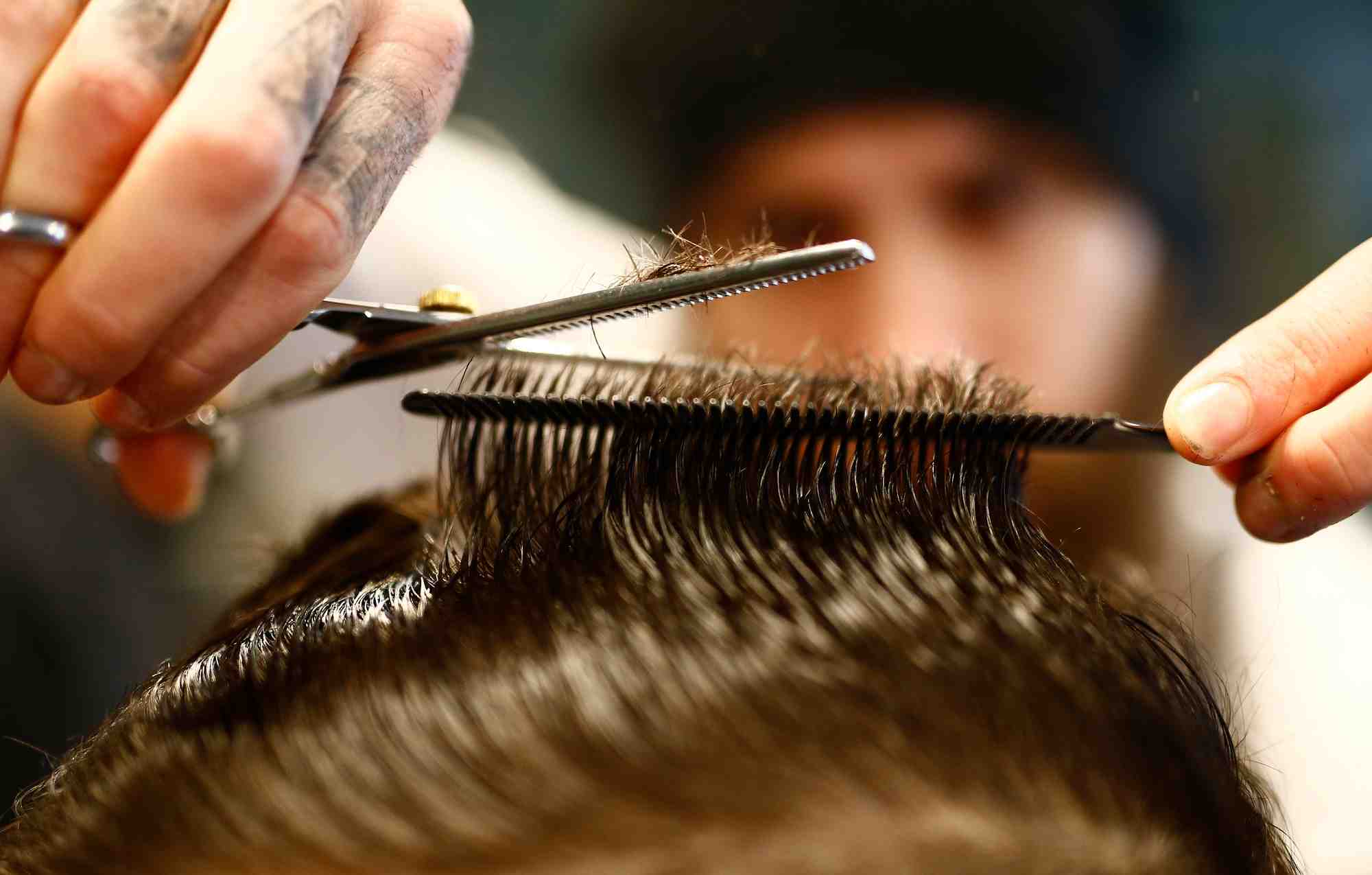 Coiffeur vellios se concentre sur le coiffage d'un client dans son salon de coiffure de torreto a francfort