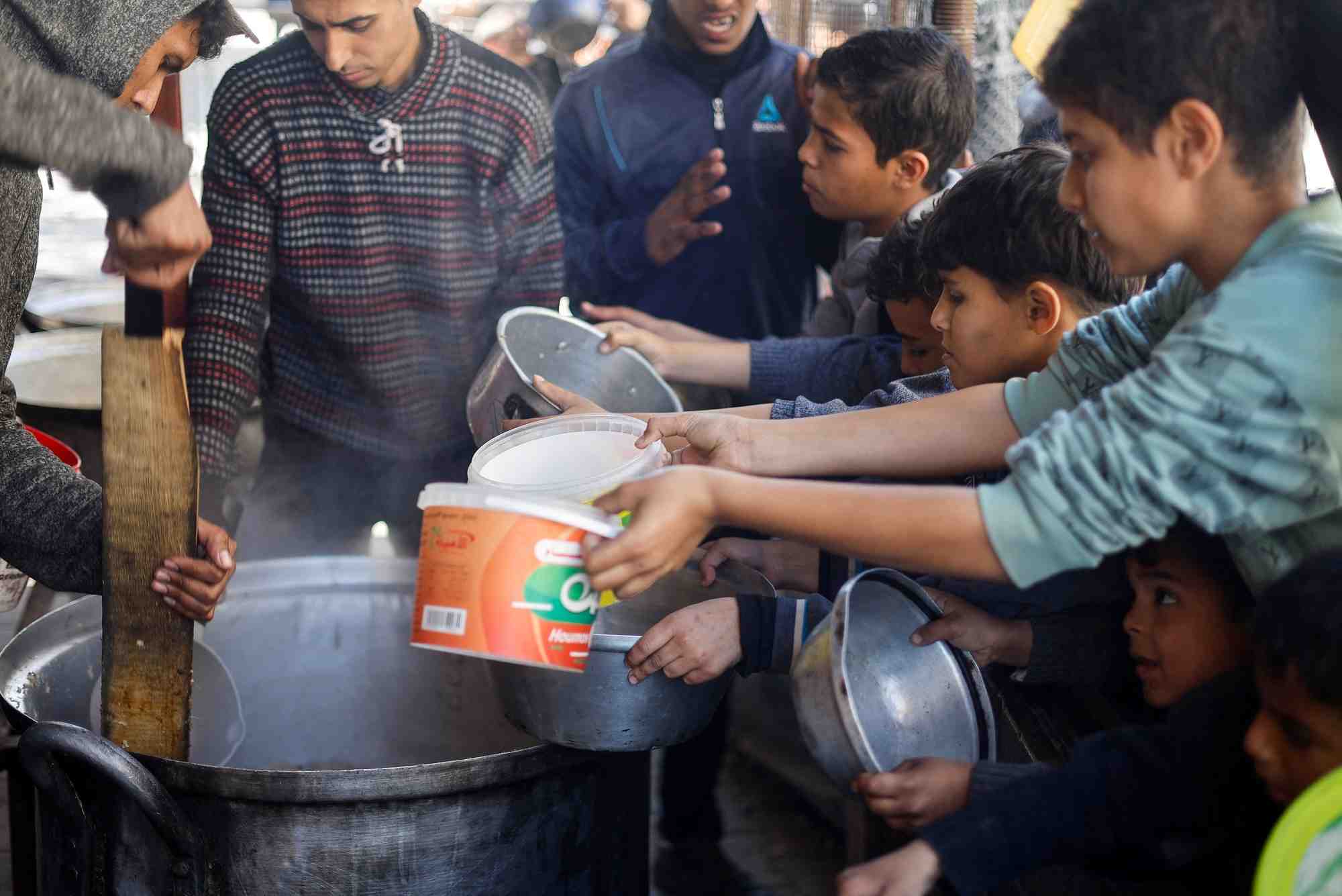 Des enfants palestiniens attendent de recevoir de la nourriture a rafah