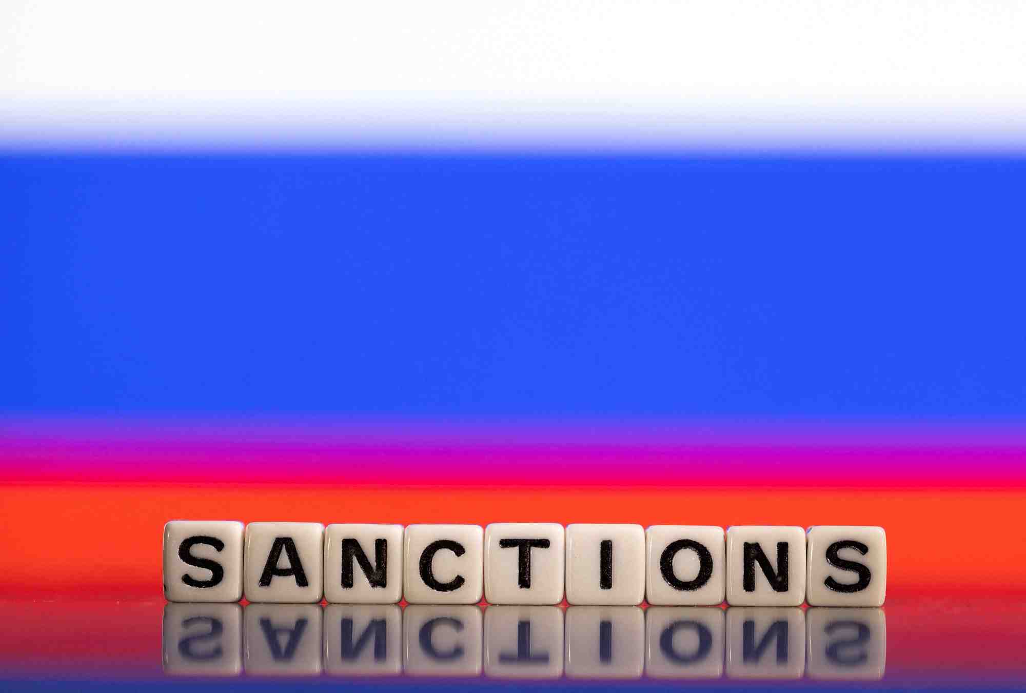 Illustration des lettres disant "sanctions" devant le drapeau russe
