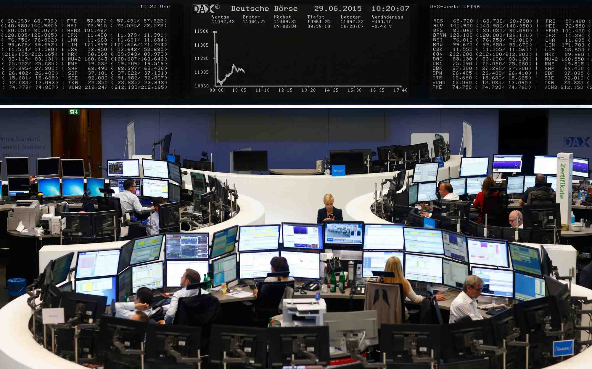 Des traders sont assis a leurs bureaux devant le tableau du dax a la bourse de francfort