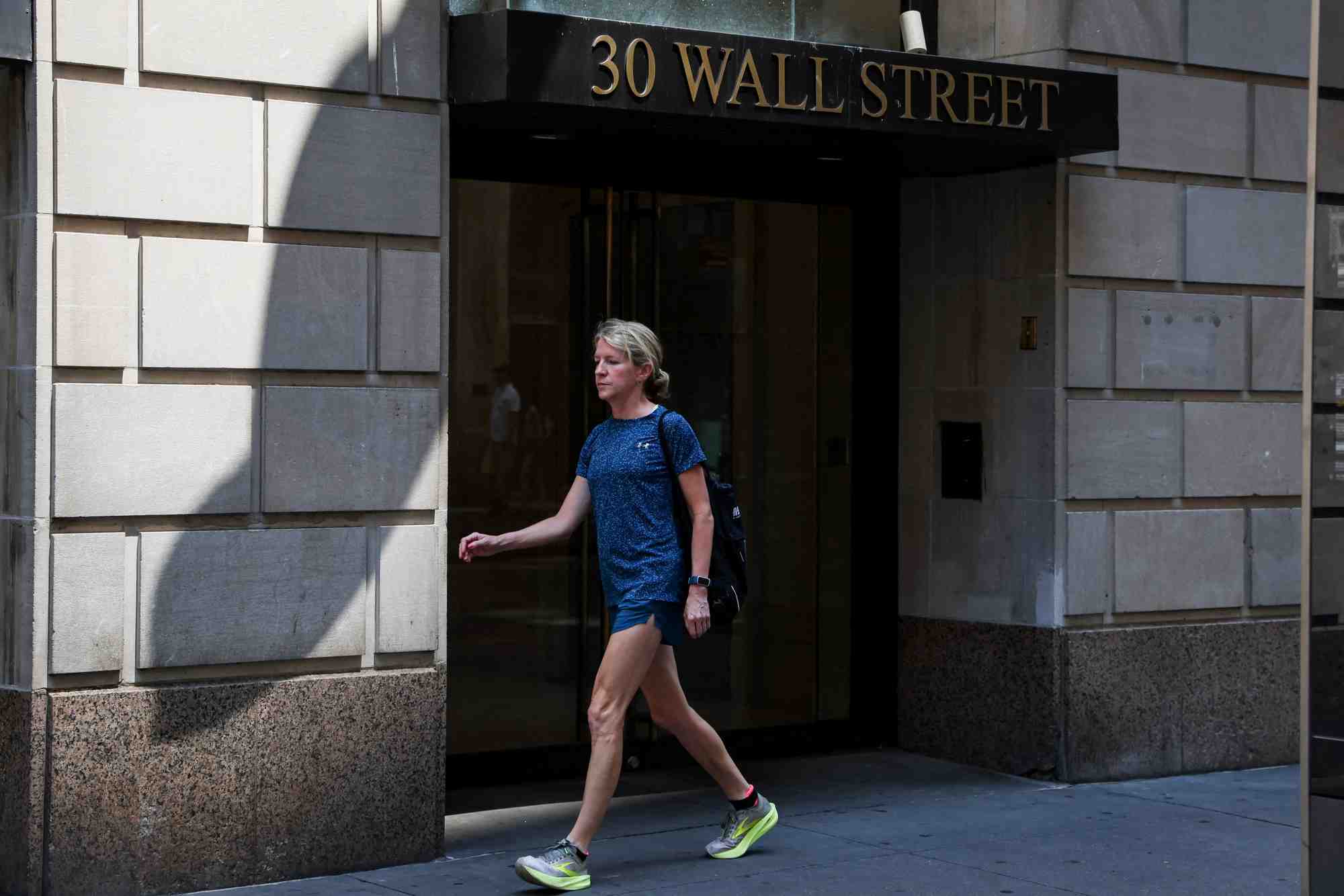 Une pietonne passe devant un batiment de wall street a new york