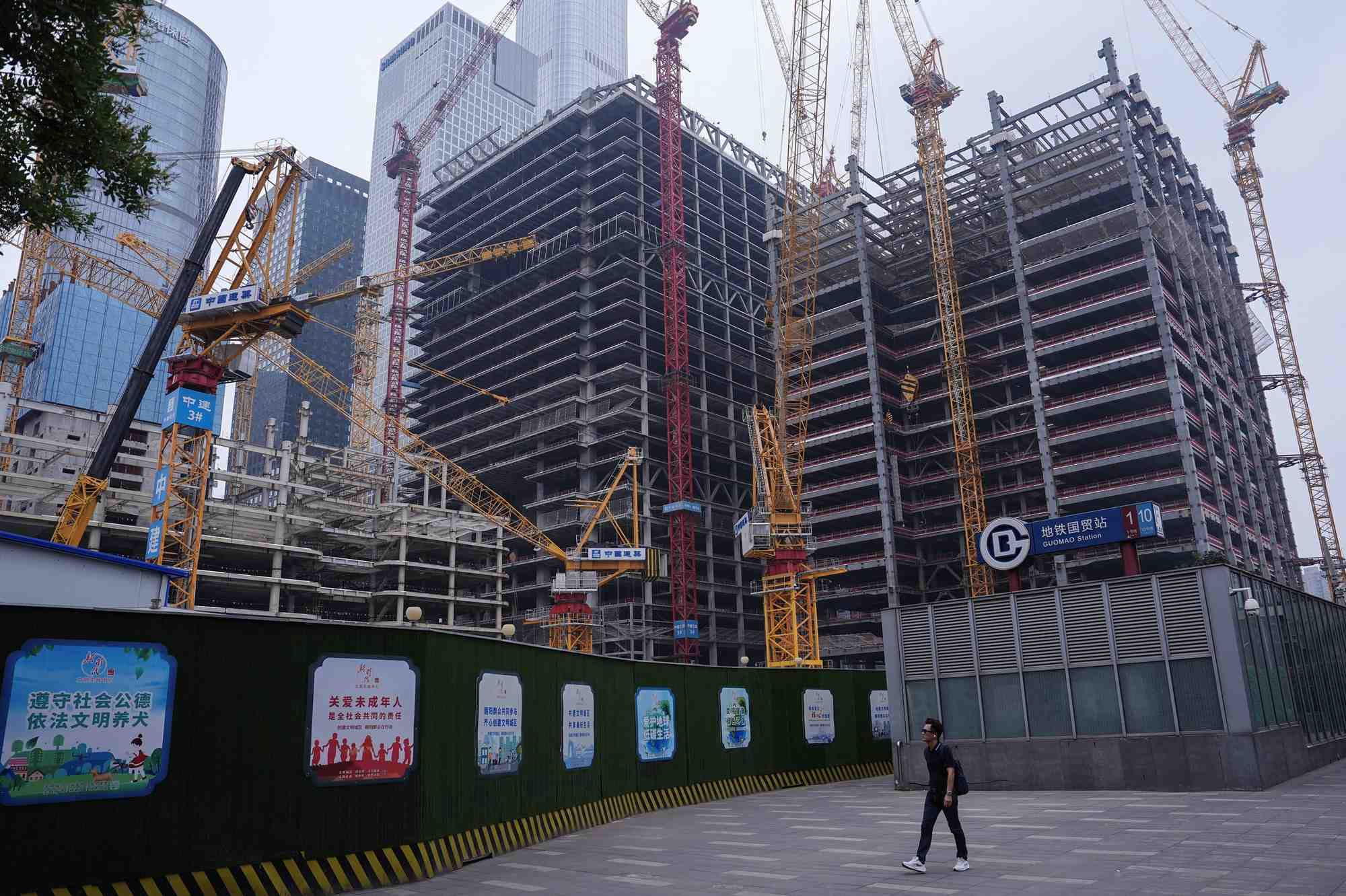 Une personne passe devant un chantier de construction dans le quartier central des affaires (cbd) de pekin.