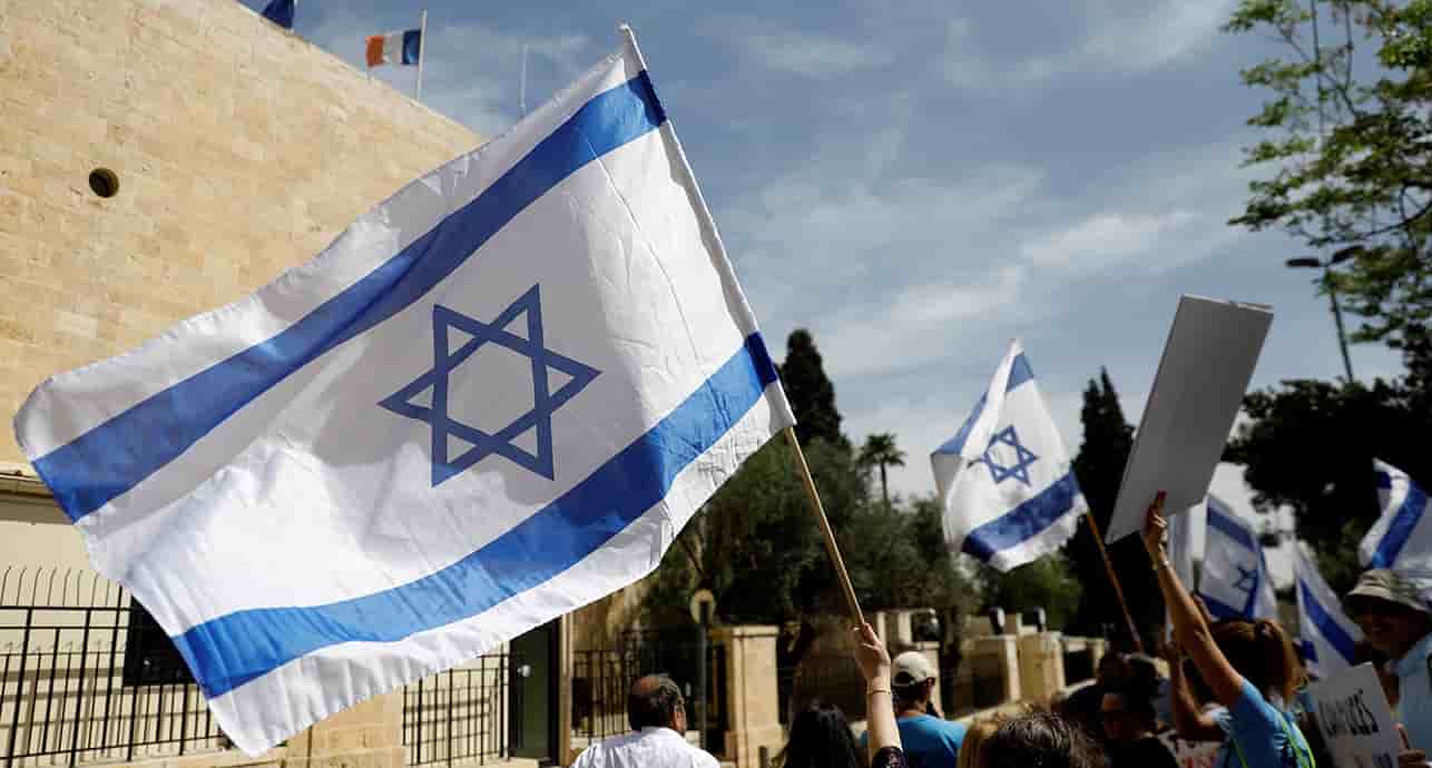 Des manifestants brandissent des drapeaux israéliens devant le consulat français à Jérusalem.