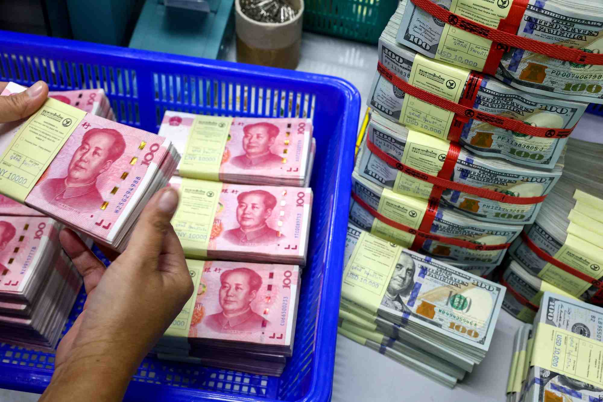 Un employe de banque compte les billets en renminbi (rmb) ou yuan de la chine a cote des billets en dollars americains dans une kasikornbank a bangkok