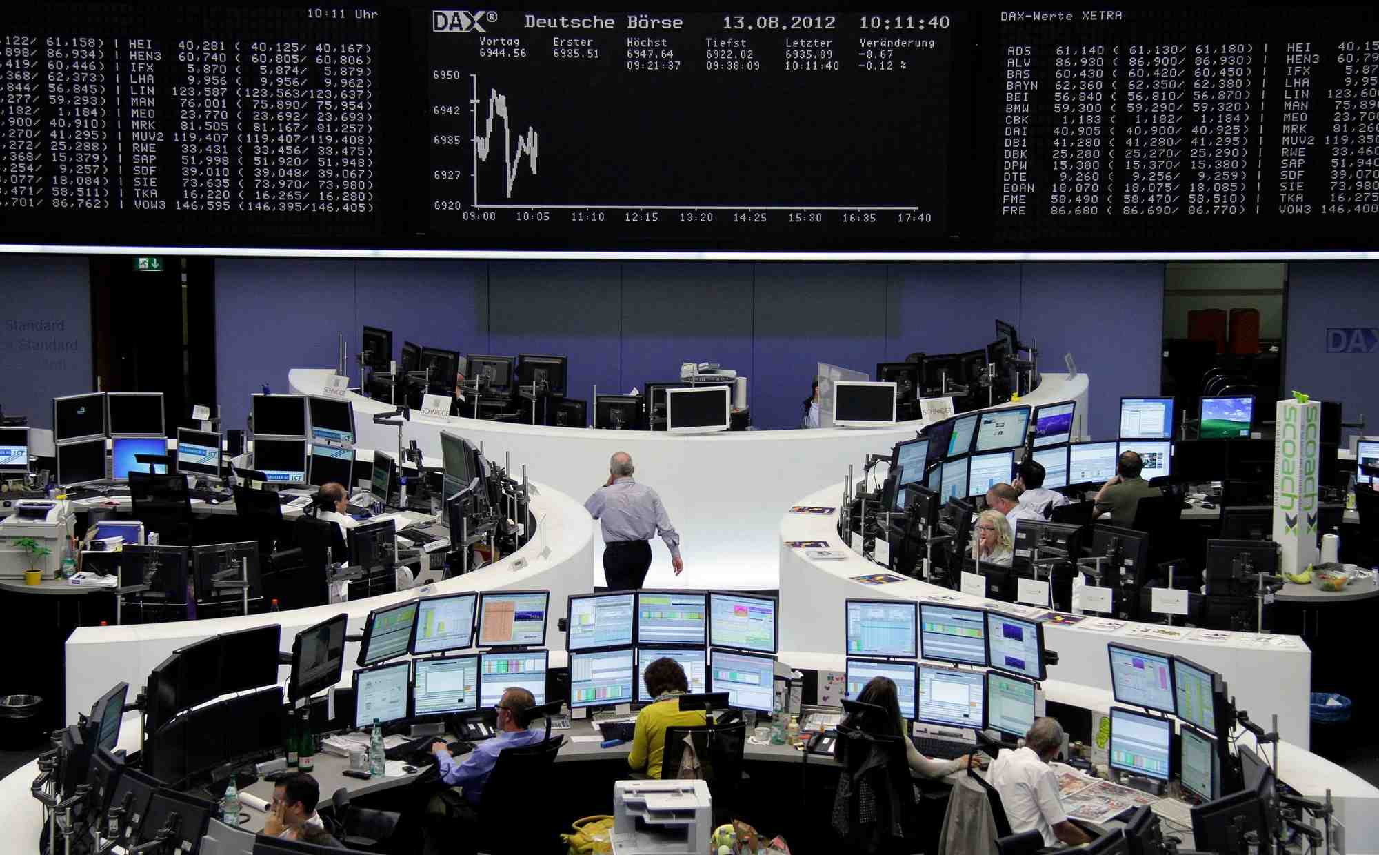 Des courtiers sont assis a leurs bureaux devant le tableau du dax a la bourse de francfort