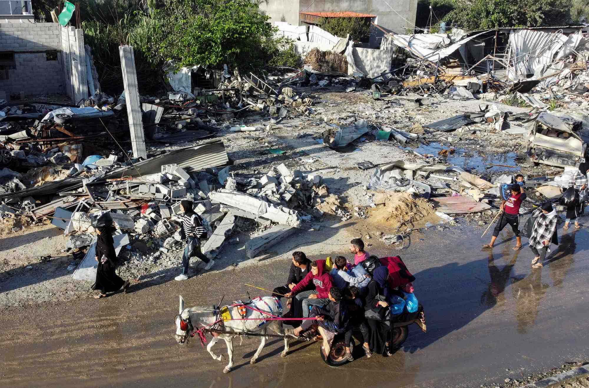 Des palestiniens deplaces rentrent chez eux et passent devant une maison detruite par une attaque israelienne a khan younis, pendant la treve conclue entre le hamas et israel