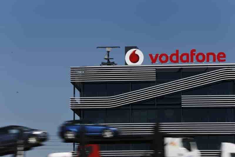 A truck carrying cars speeds past the headquarters of vodafone in madrid
