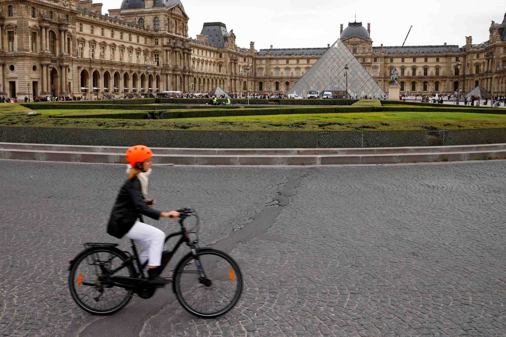 Une femme circule en velo pres de la pyramide du musee du louvre a paris
