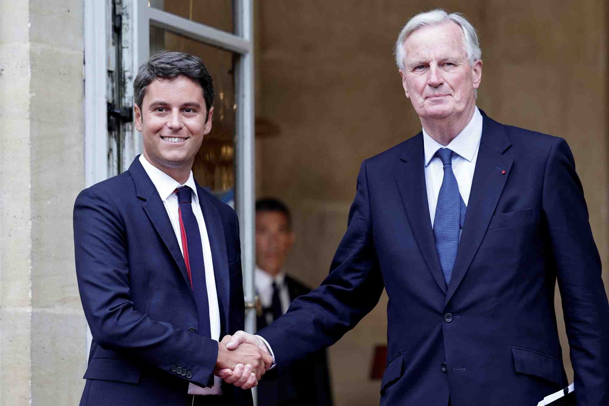 Le nouveau premier ministre michel barnier serre la main du premier ministre sortant gabriel attal lors de la ceremonie de passation des pouvoirs a l'hotel matignon a paris