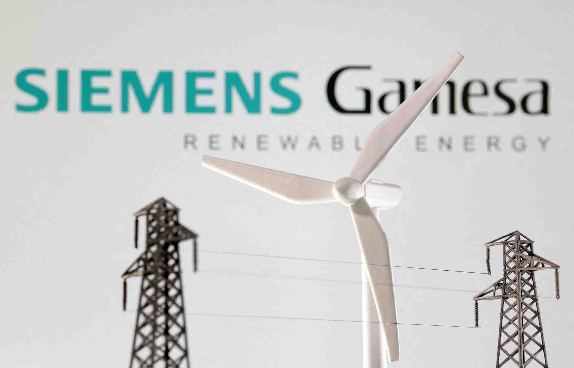 Des miniatures d'eoliennes et de poteaux electriques devant le logo de siemens gamesa