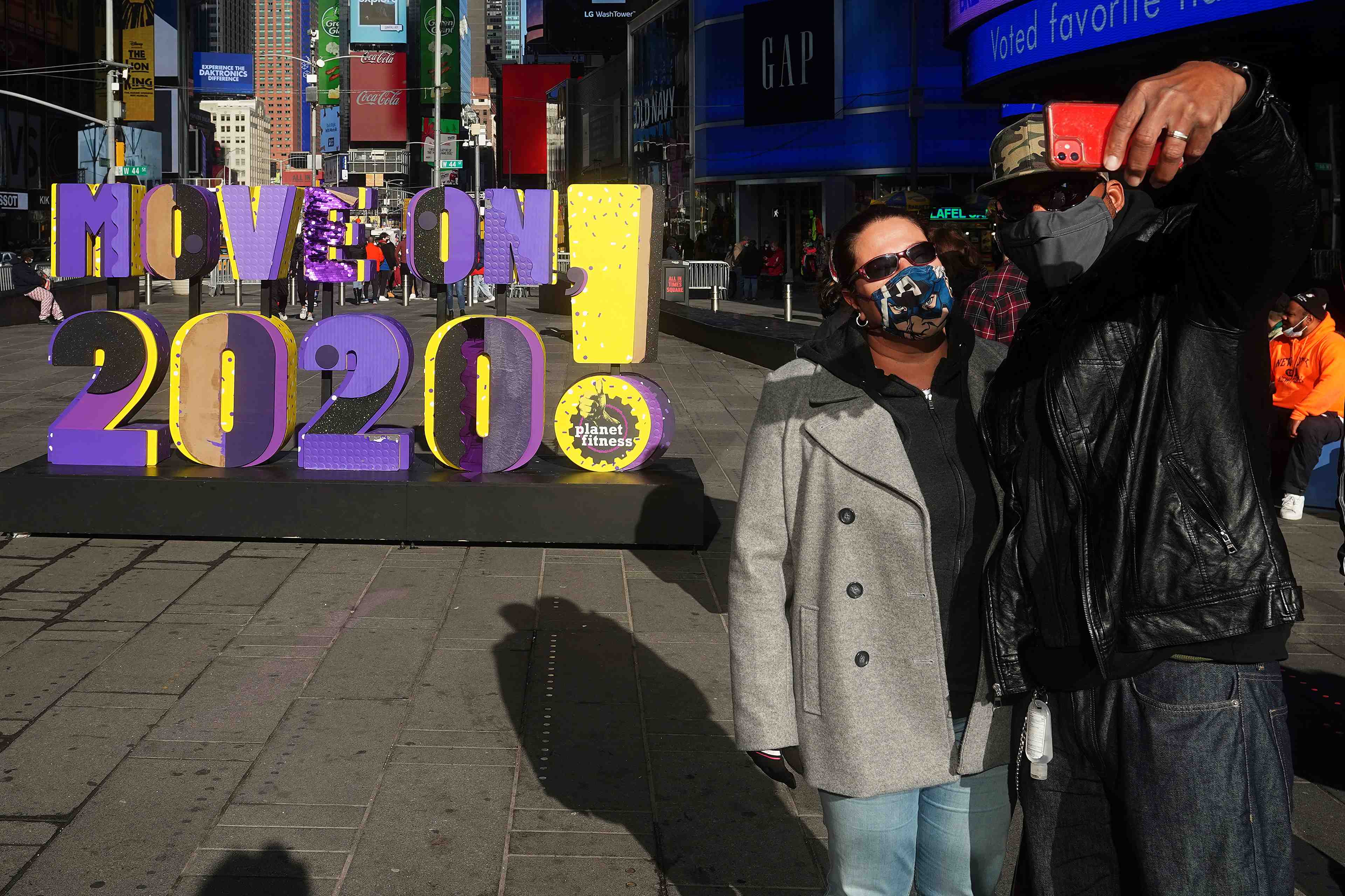 People take a selfie in front of a "move on 2020!" sign in times square