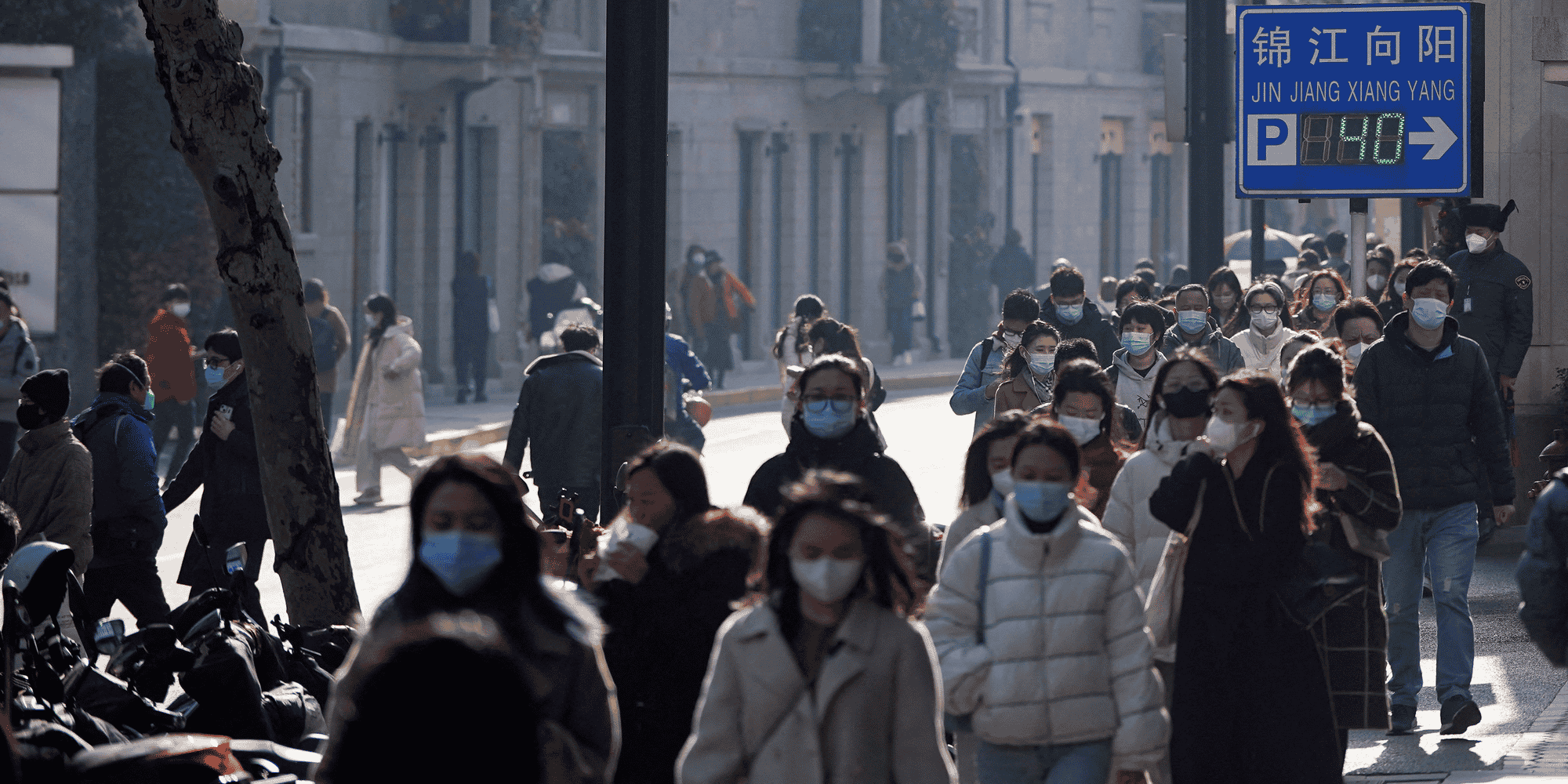 Des personnes portant des masques de protection marchent dans une rue a shanghai, en chine