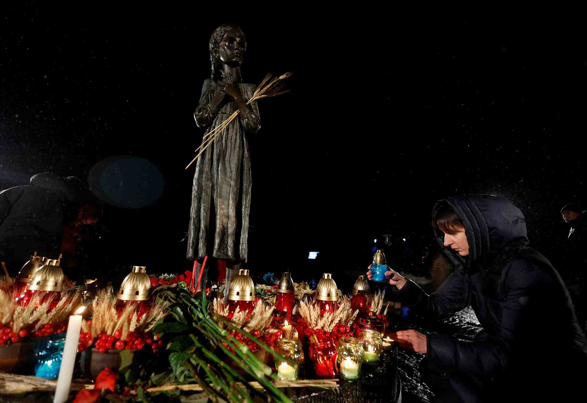 Une femme place une bougie devant un monument aux victimes de l'holodomor