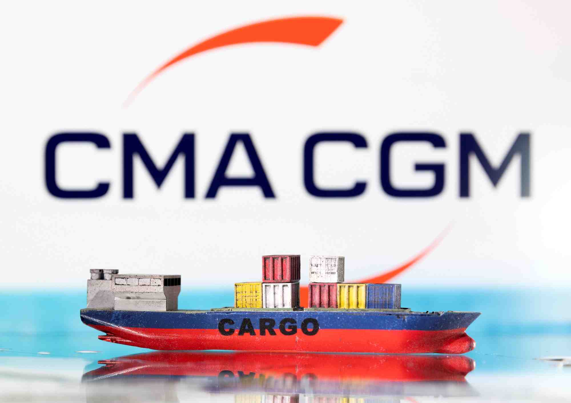 Photo d'illustration d'un modele de bateau cargo devant le logo de cma cgm