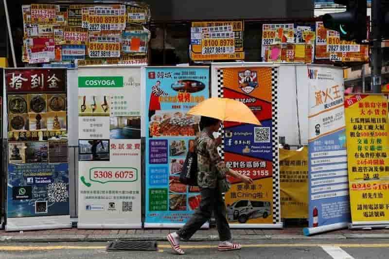A woman walks past banners promoting retail goods and services displayed in front of closed shops for rent at the shopping mongkok district in hong kong