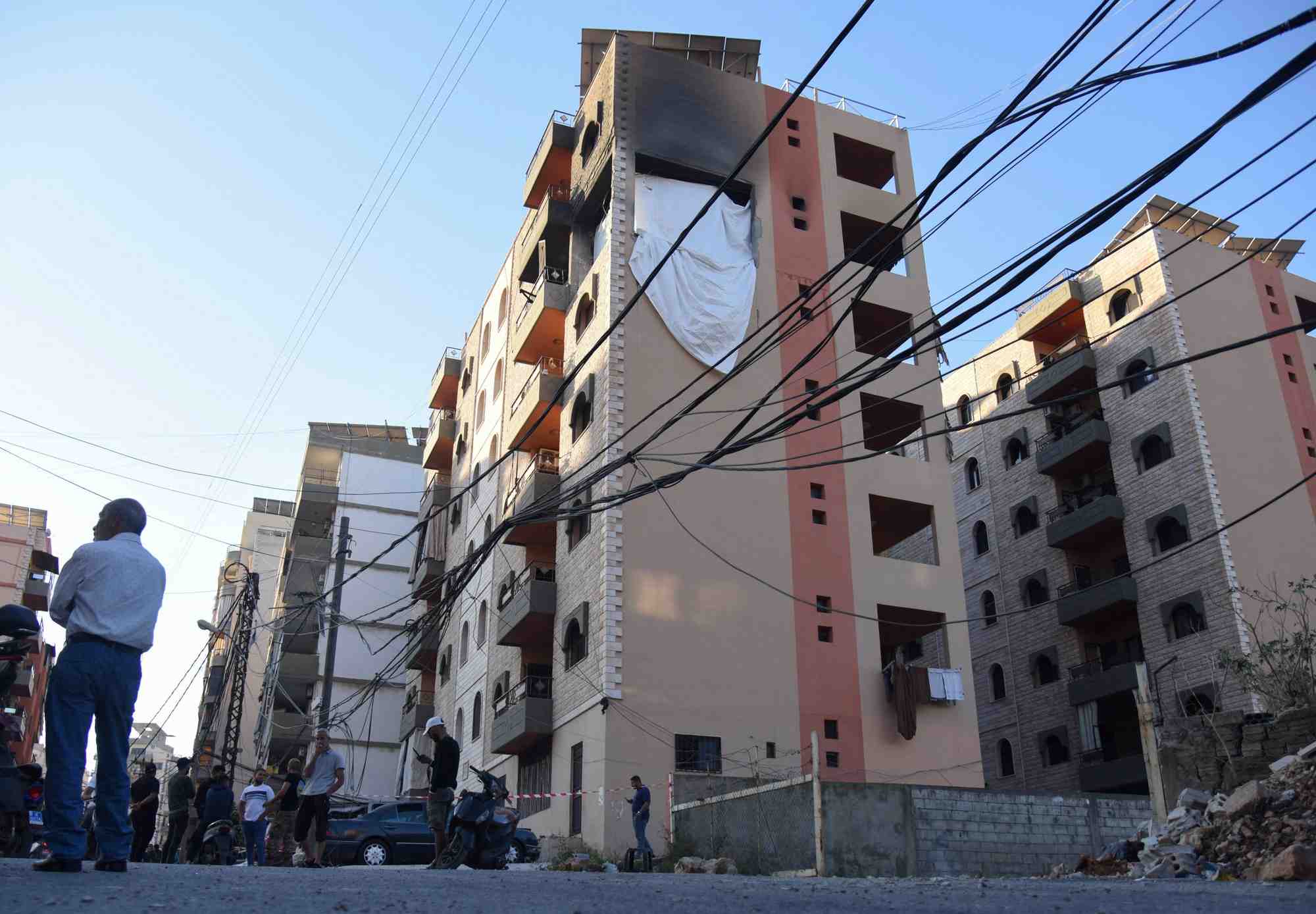 Des personnes se tiennent sur le site touche par une frappe israelienne dans la ville de tripoli, au liban
